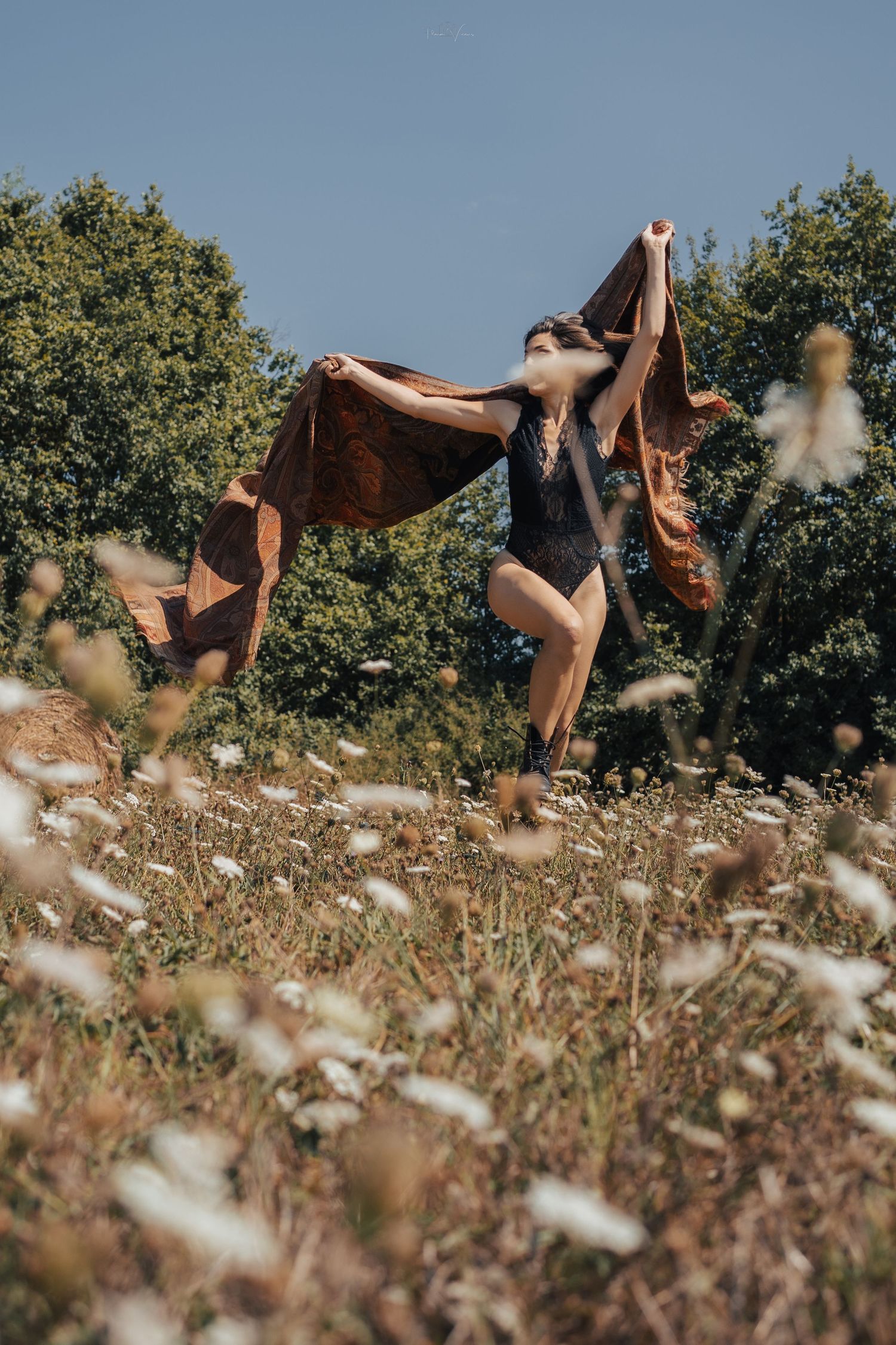 A creative photoshoot in a wildflower meadow with flowing fabric and natural lighting.