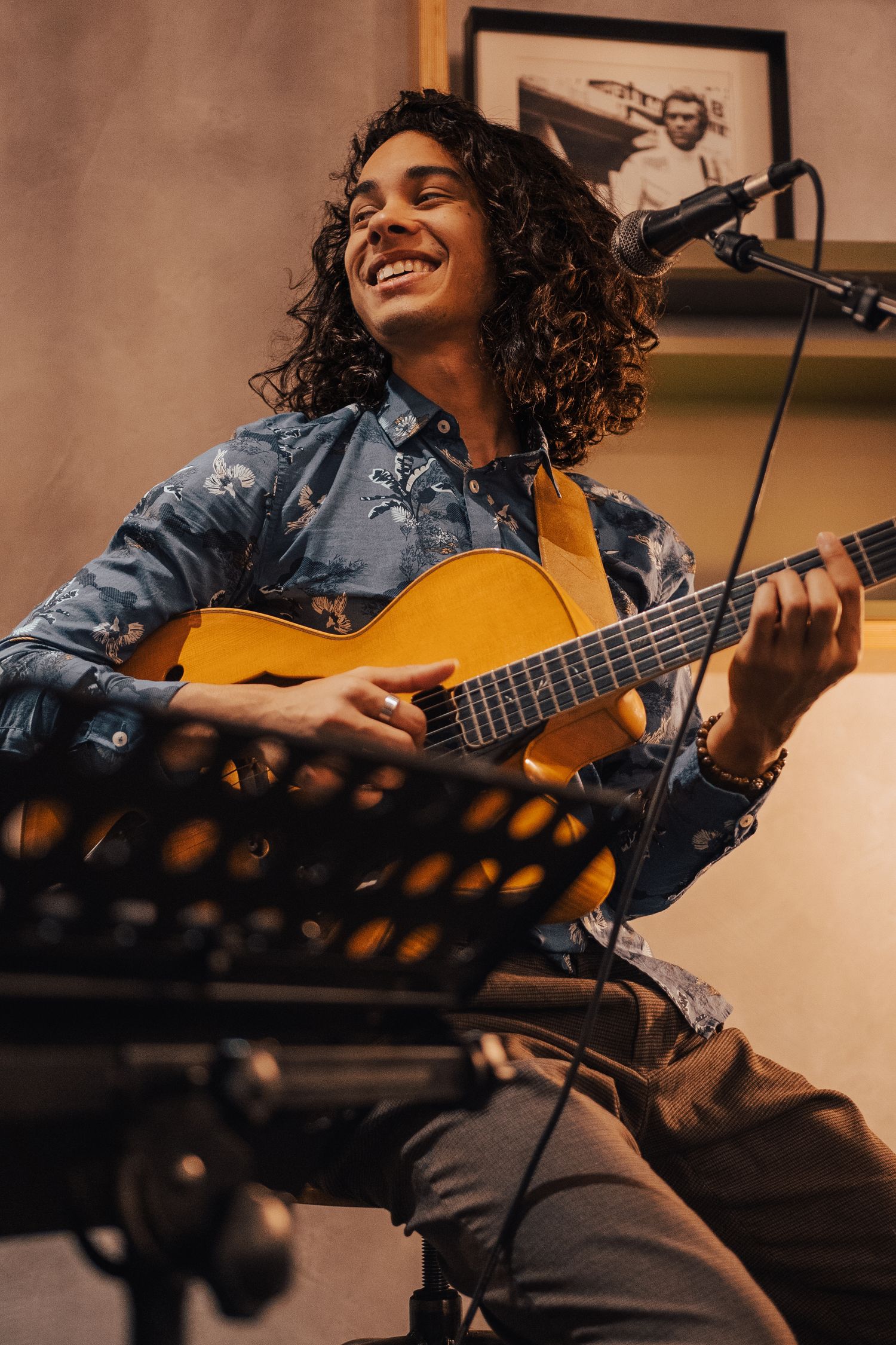 Musician playing acoustic guitar with expressive joy in a recording studio setting.