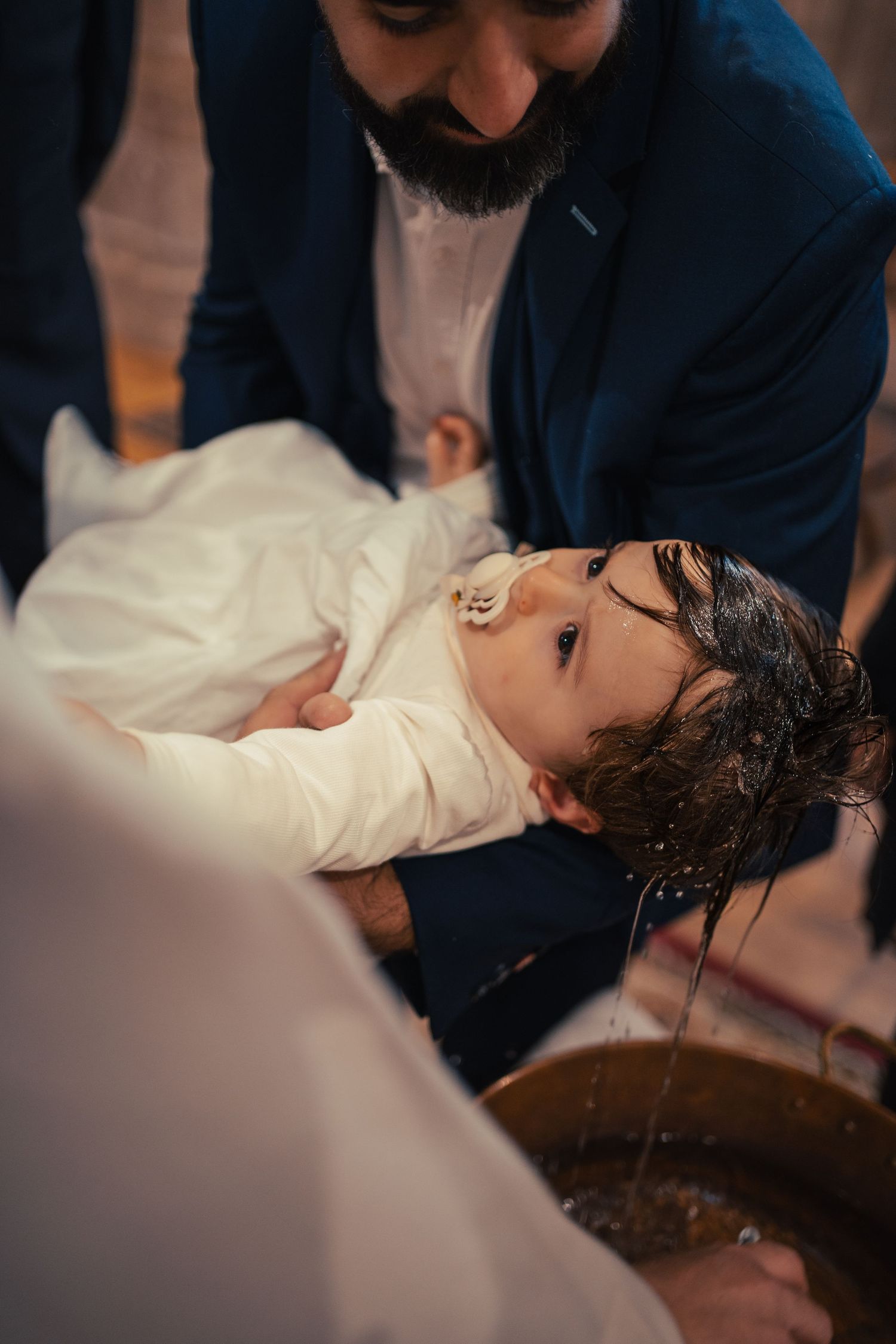 Religious baptism ceremony captured in intimate detail with dramatic lighting.
