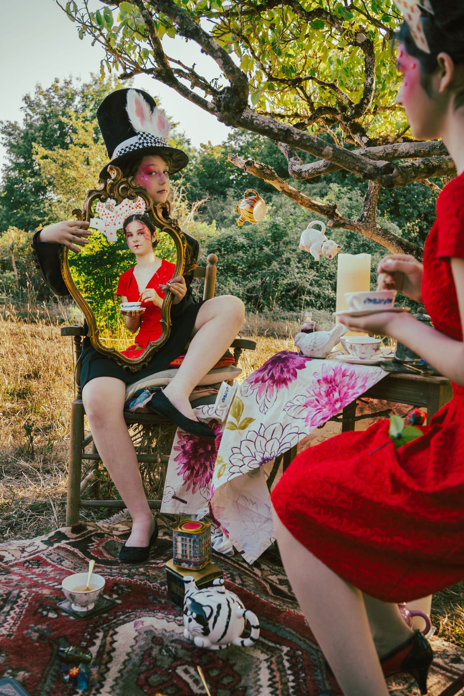 Outdoor tea party setting with vintage teacups and floral decorations under tree.