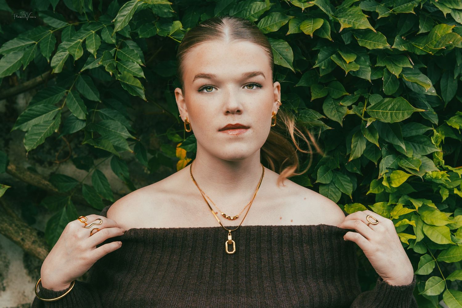 Portrait framed by lush green foliage in natural lighting.