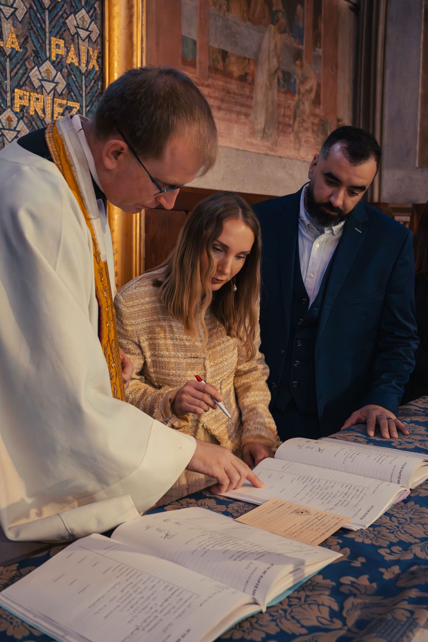 People signing official documents during a formal ceremony in a church setting.