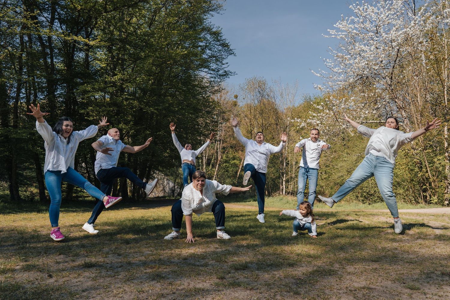 People jumping and posing playfully on a grassy hillside during a sunny day.