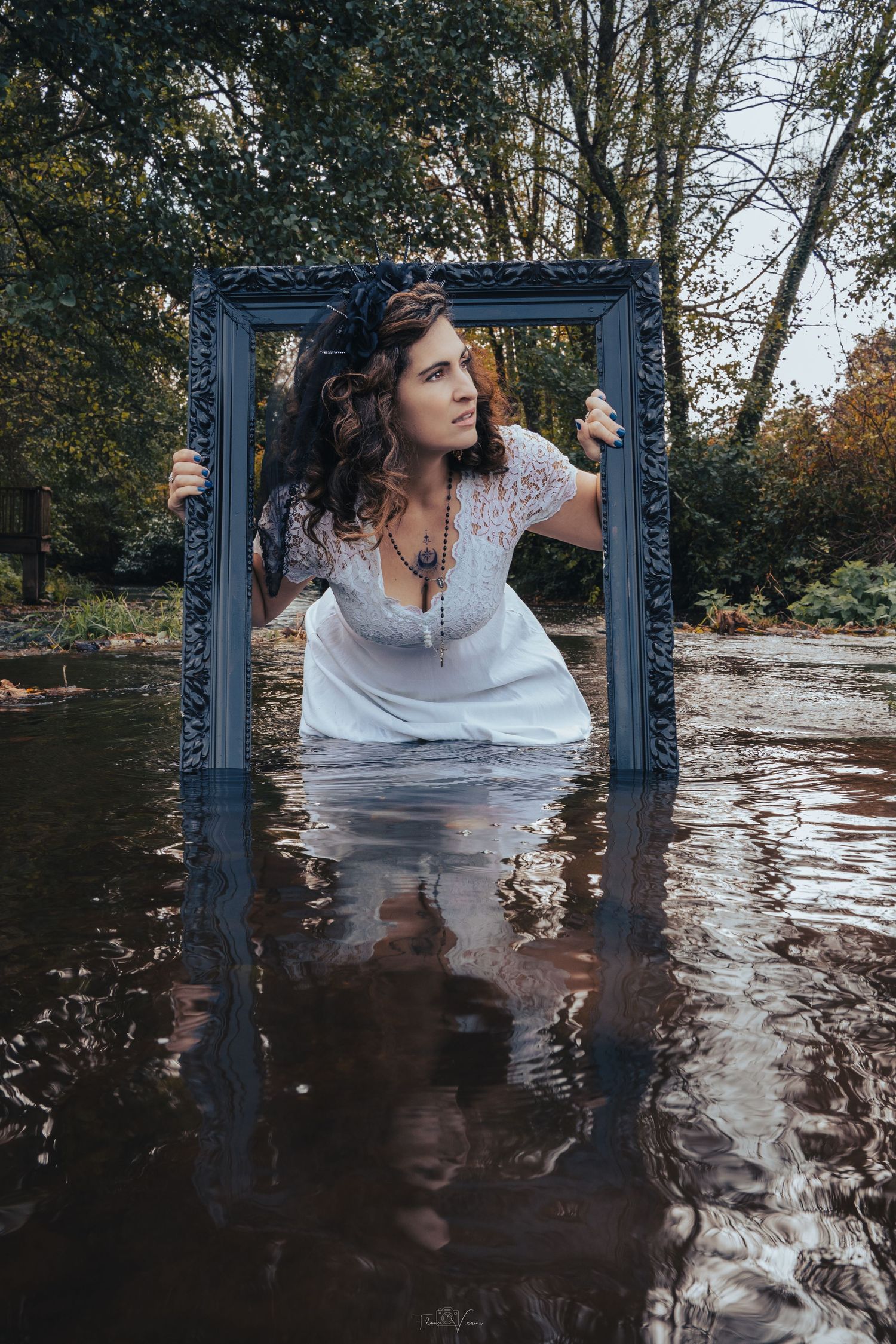 An artistic portrait taken through a blue frame in reflective water surrounded by autumn trees.