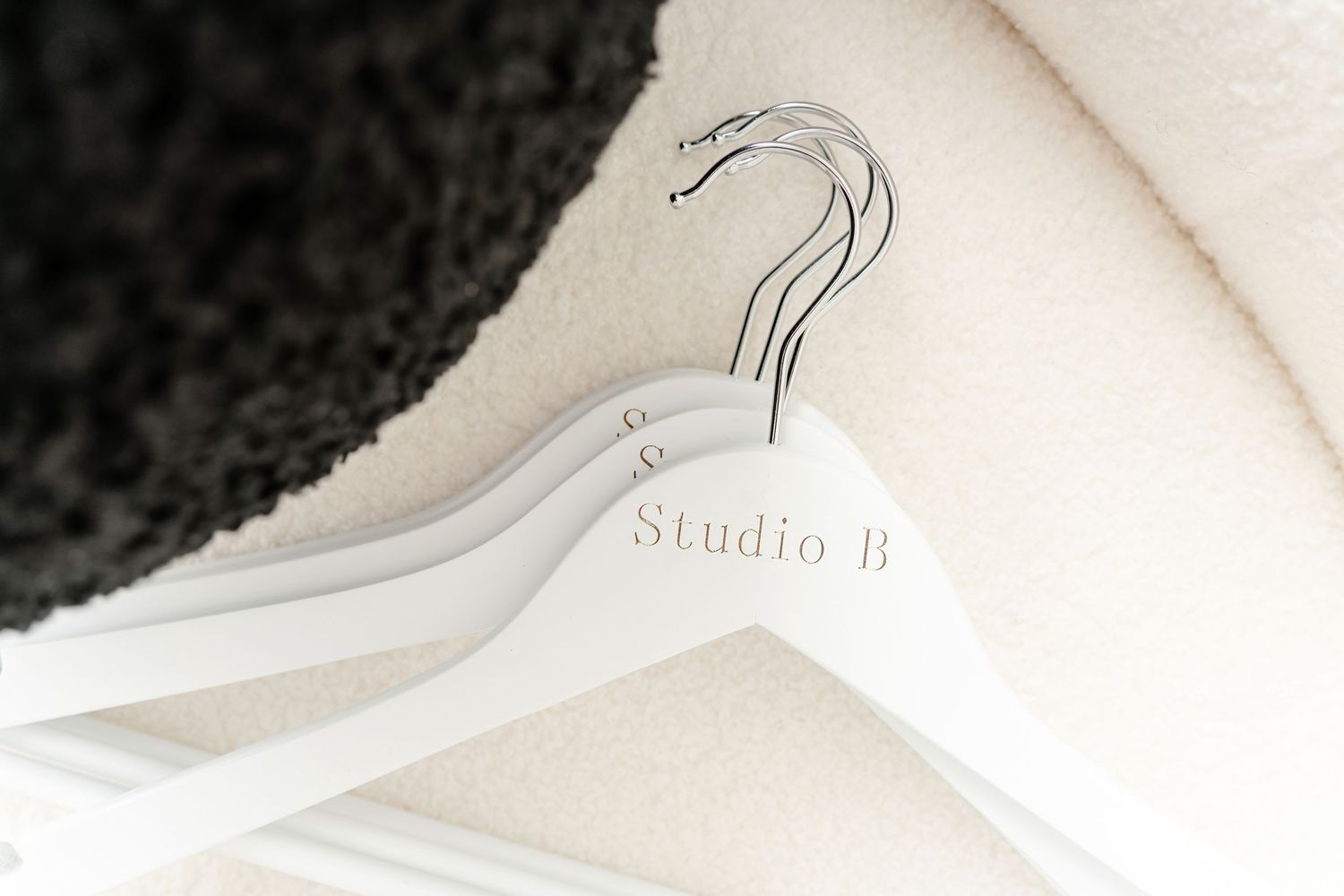 White clothes hanger with Studio b text and minimalist crane design.