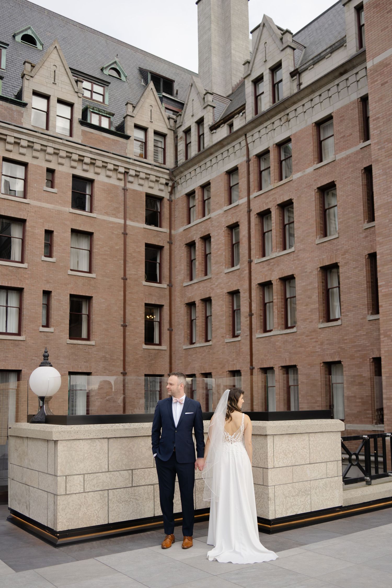 Architectural wedding portraits with brick and stone building creating dramatic backdrop.