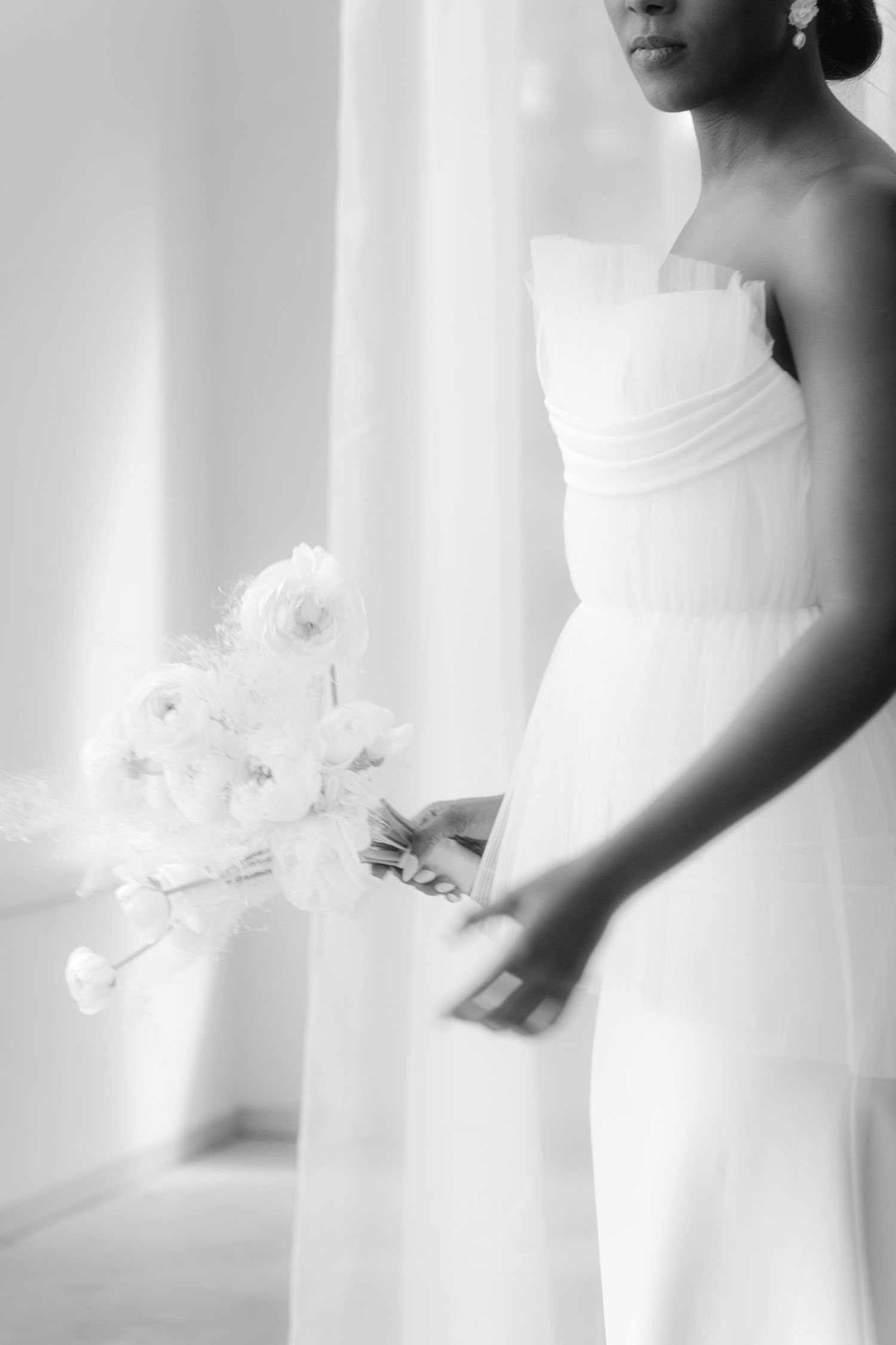 Elegant white bridal gown details showing delicate floral embellishments and fabric textures against a light background.