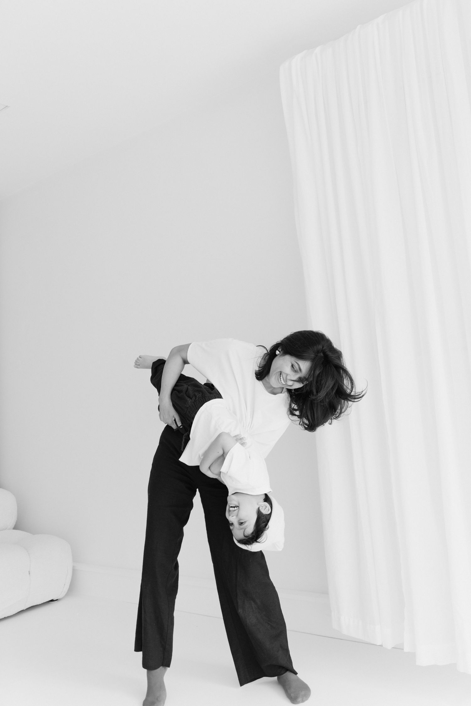 Black and white portrait showing dynamic movement in minimal white studio setting.