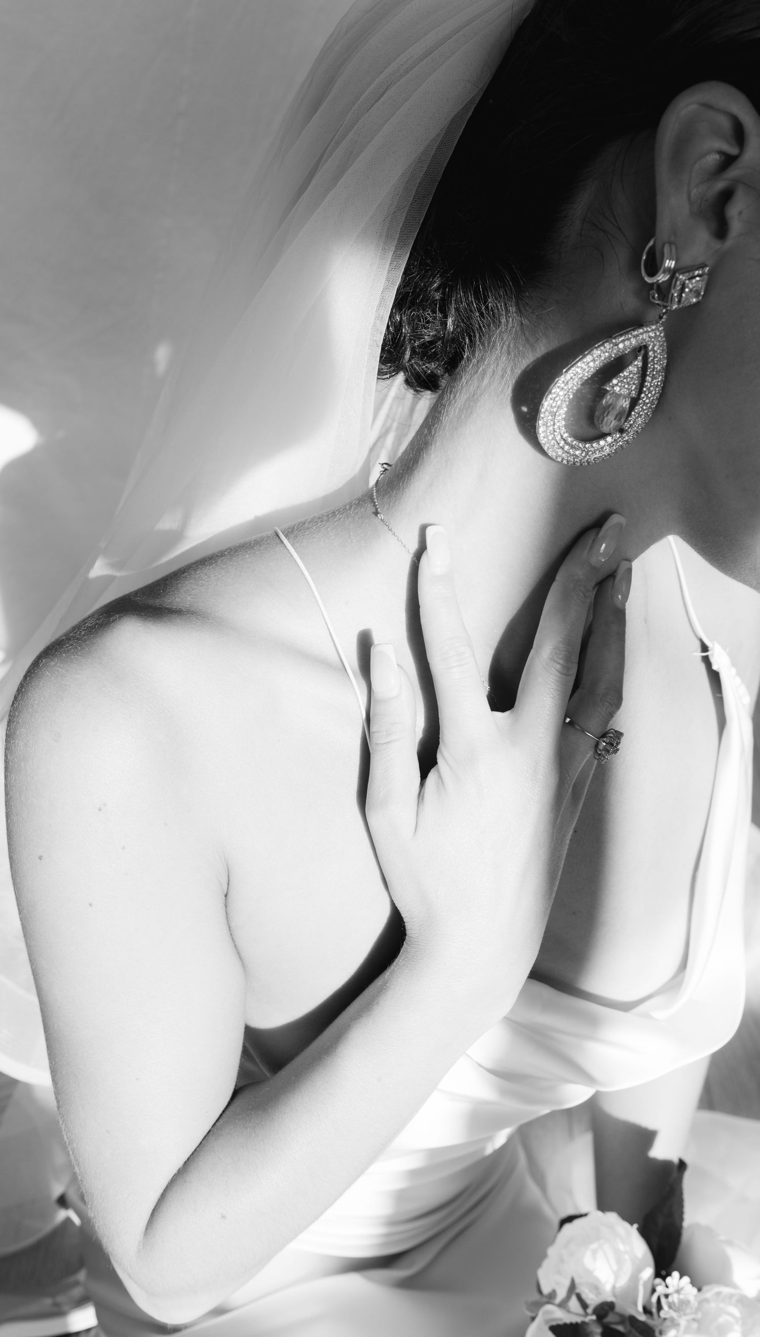 Artistic black and white portrait showing elegant bridal details and jewelry.
