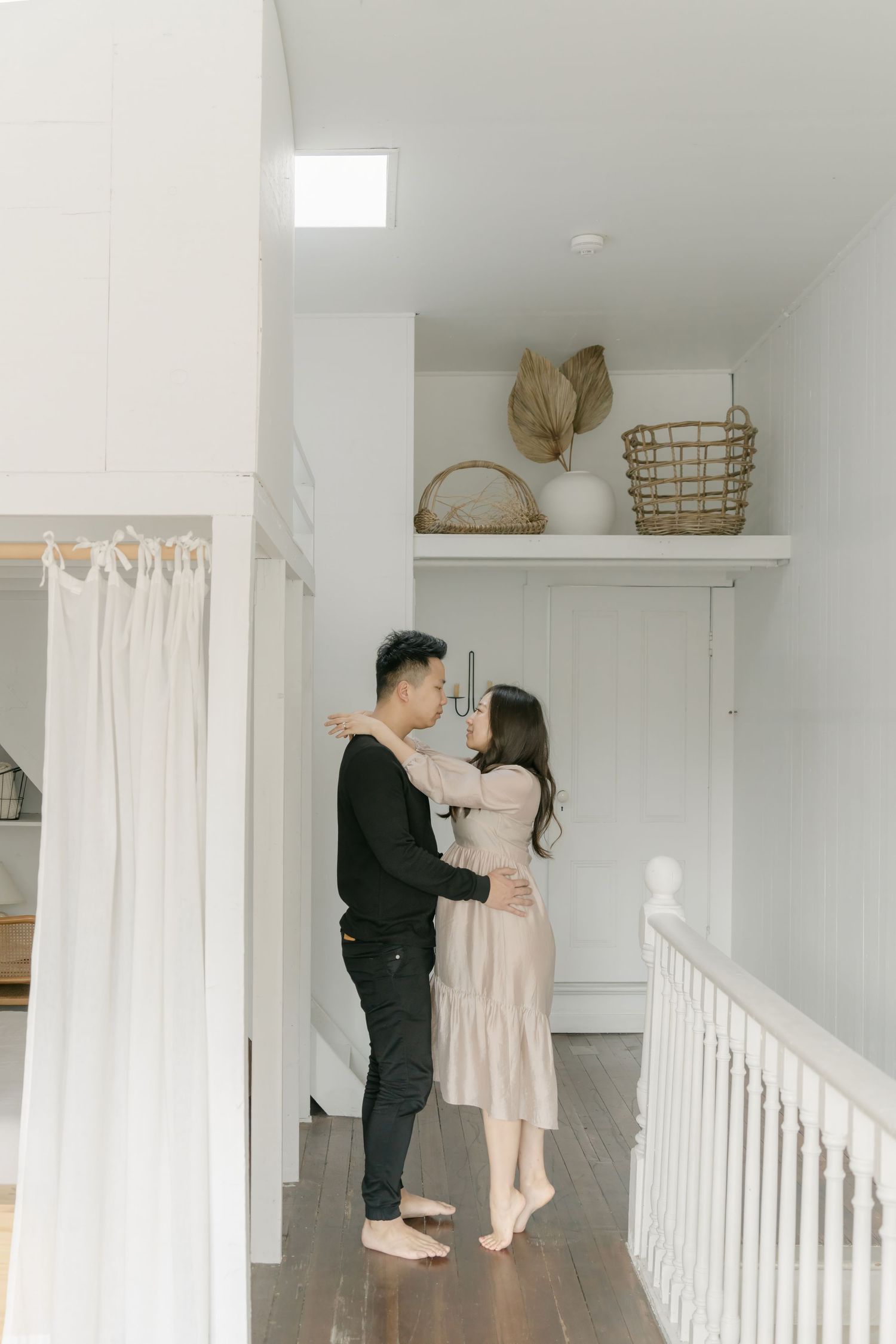 Intimate photoshoot in a bright white hallway with natural lighting and minimal decor.