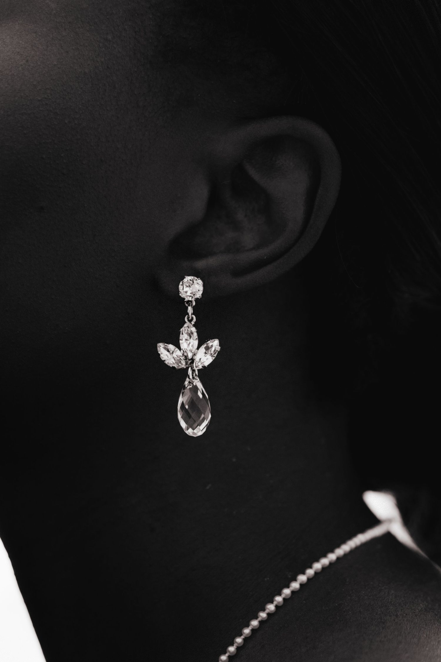 Crystal drop earrings sparkle against a dark background.