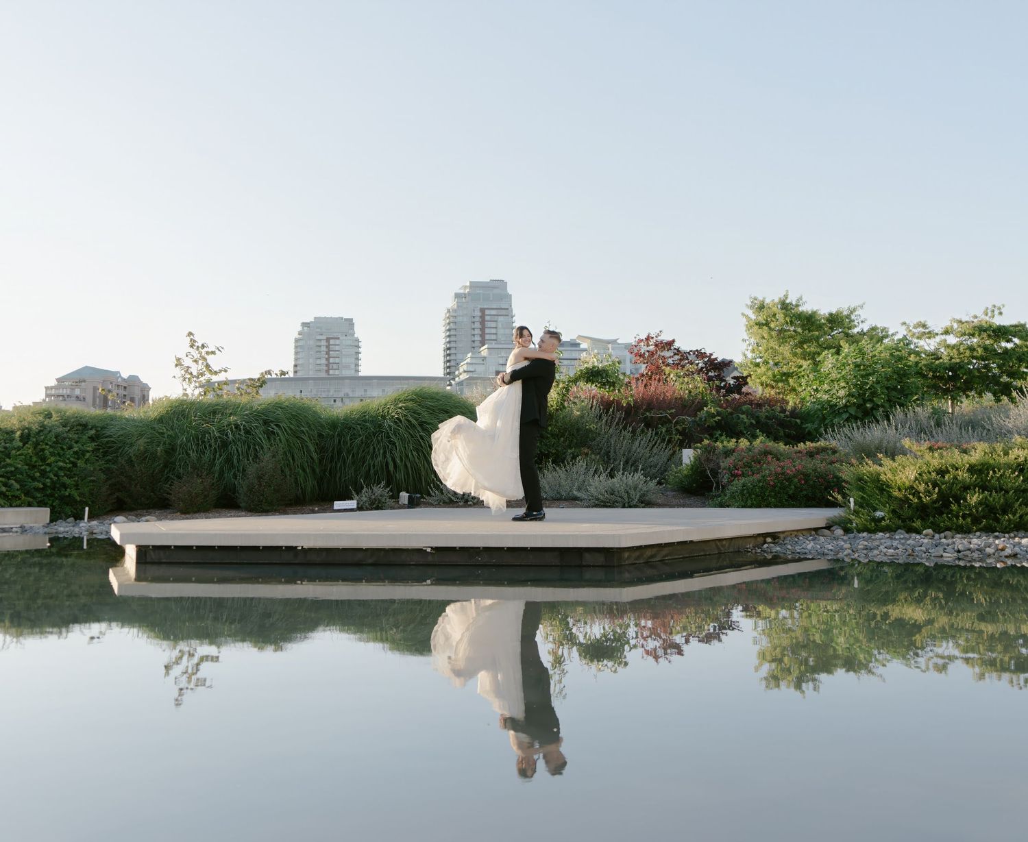 A serene waterfront wedding venue with city skyline visible in the background.