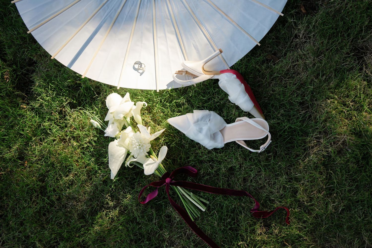 A sequence of white umbrellas arranged in an outdoor garden setting creates an artistic installation effect.