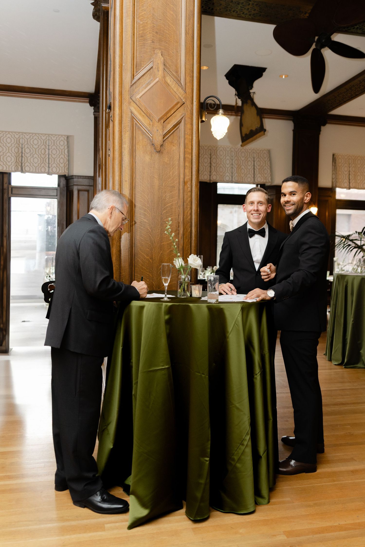 Wedding reception setup with formal tables draped in dark green linens.