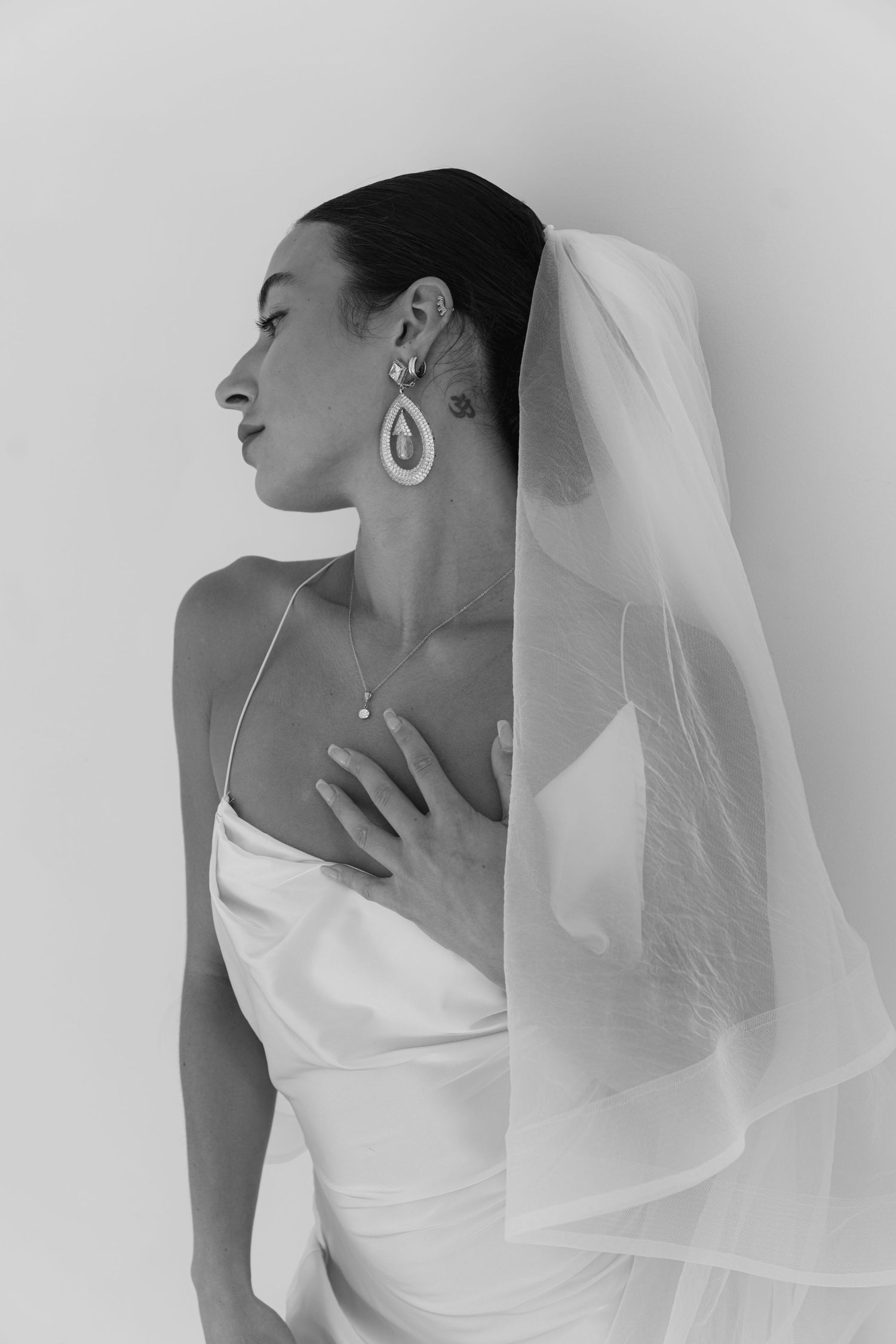 Elegant bridal portraits in white showing delicate veil details and minimalist styling against light background.