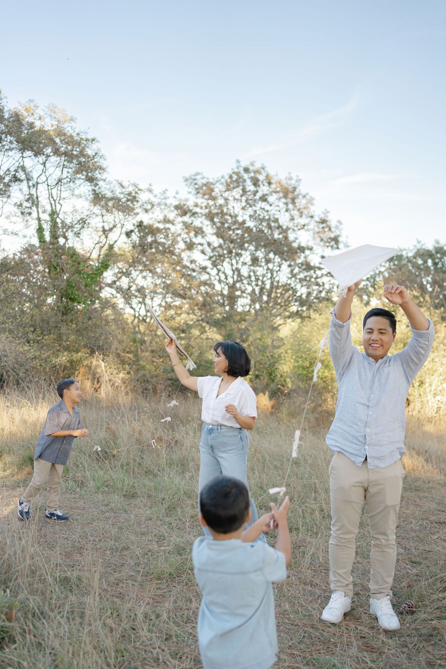 Two people in casual attire interact playfully in a grassy field during golden hour.