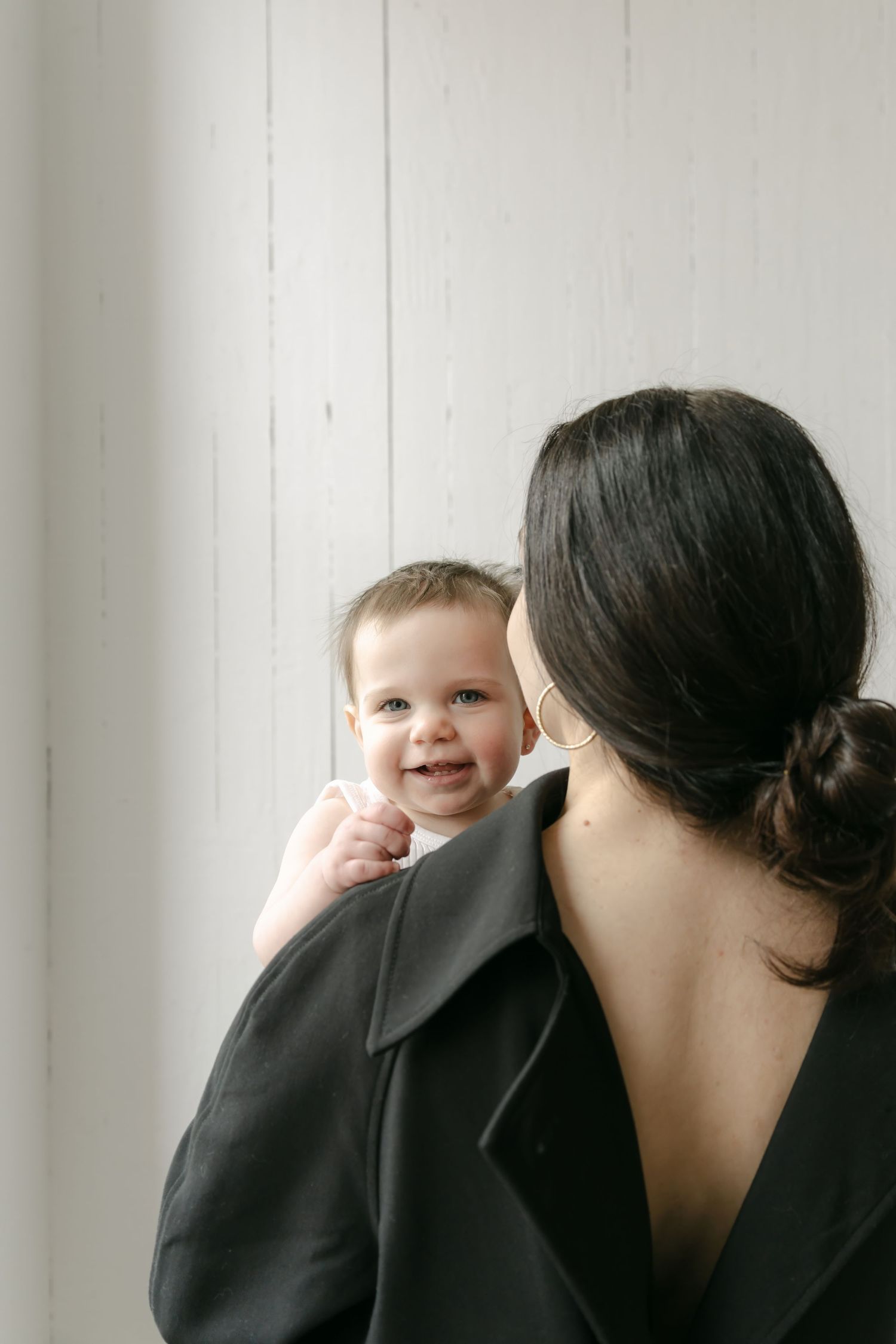 Close-up sequence in minimalist setting showing a person in black embracing a small child against a white background.