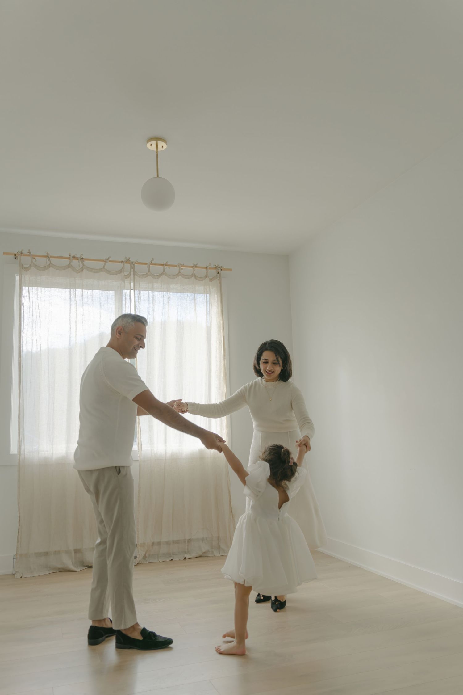 Family dancing together in bright minimalist room with sheer curtains at Lane way Studio.
