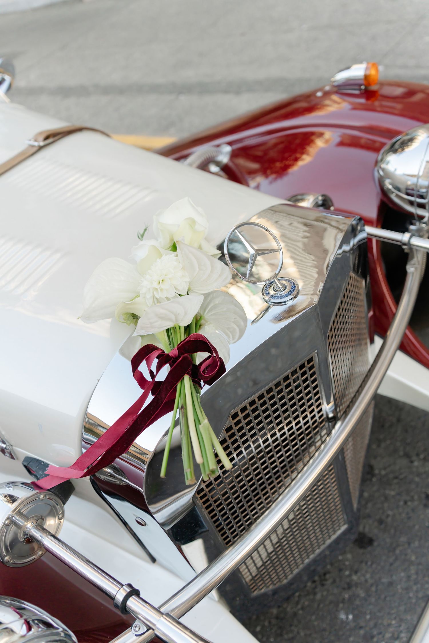 Close-up detail shots of a vintage car's chrome grille and hood ornament with decorative white flowers.