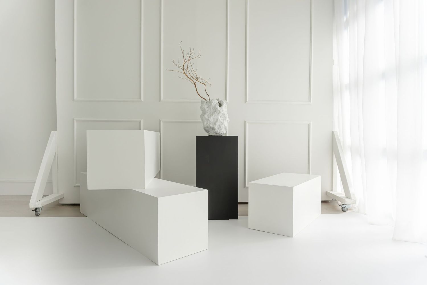 Clean white interior with geometric blocks and black accent pieces for minimal styling at Studio B.