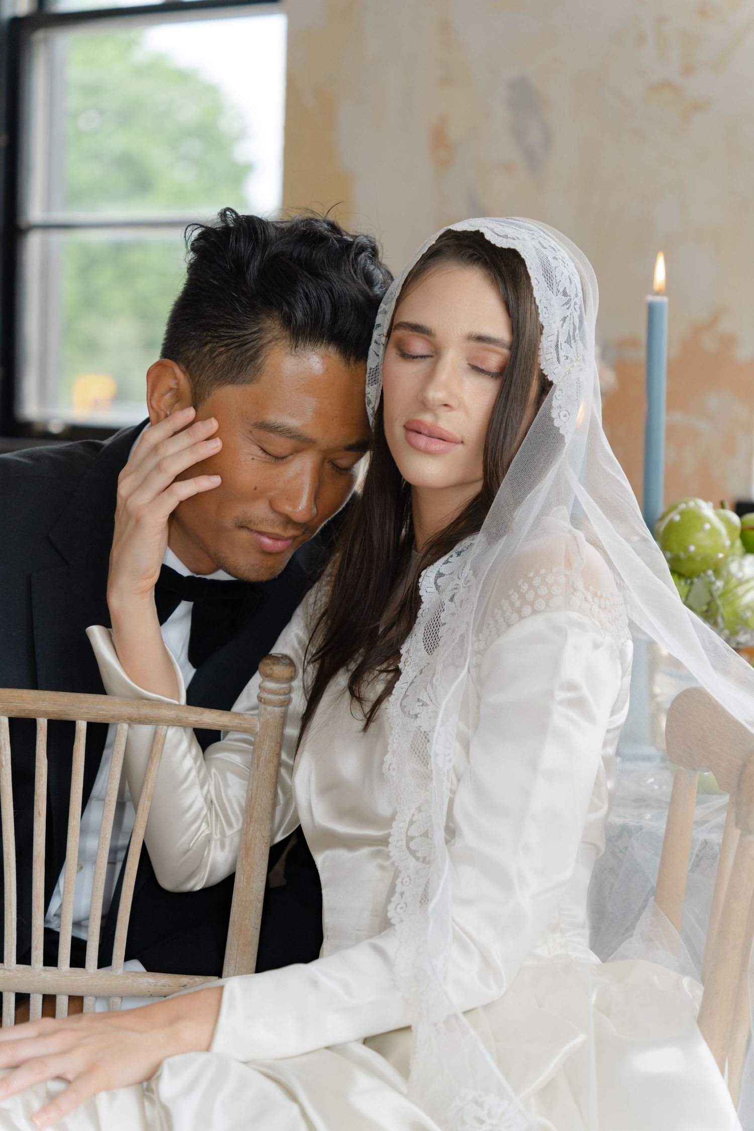 Romantic wedding couple in formal attire sharing an intimate moment at a decorated table setting.