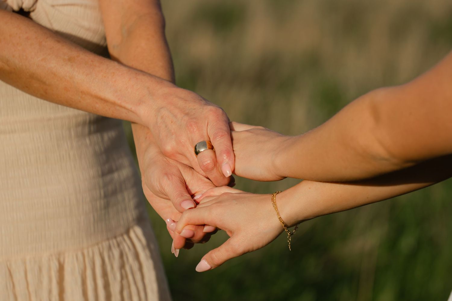 Close-up of hands exchanging rings outdoors with natural lighting.