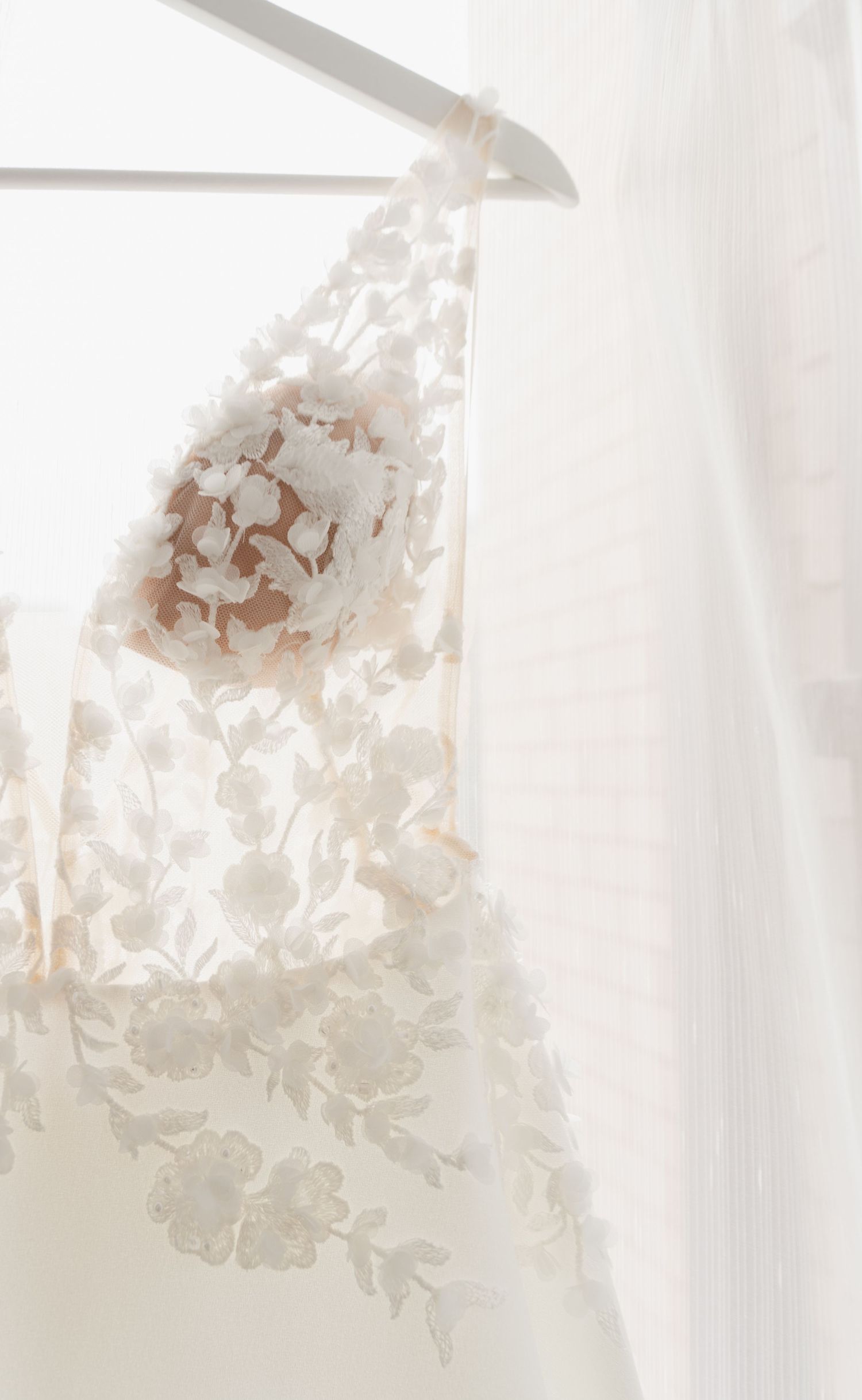 Close-up detail of delicate floral lace pattern on a white wedding dress.