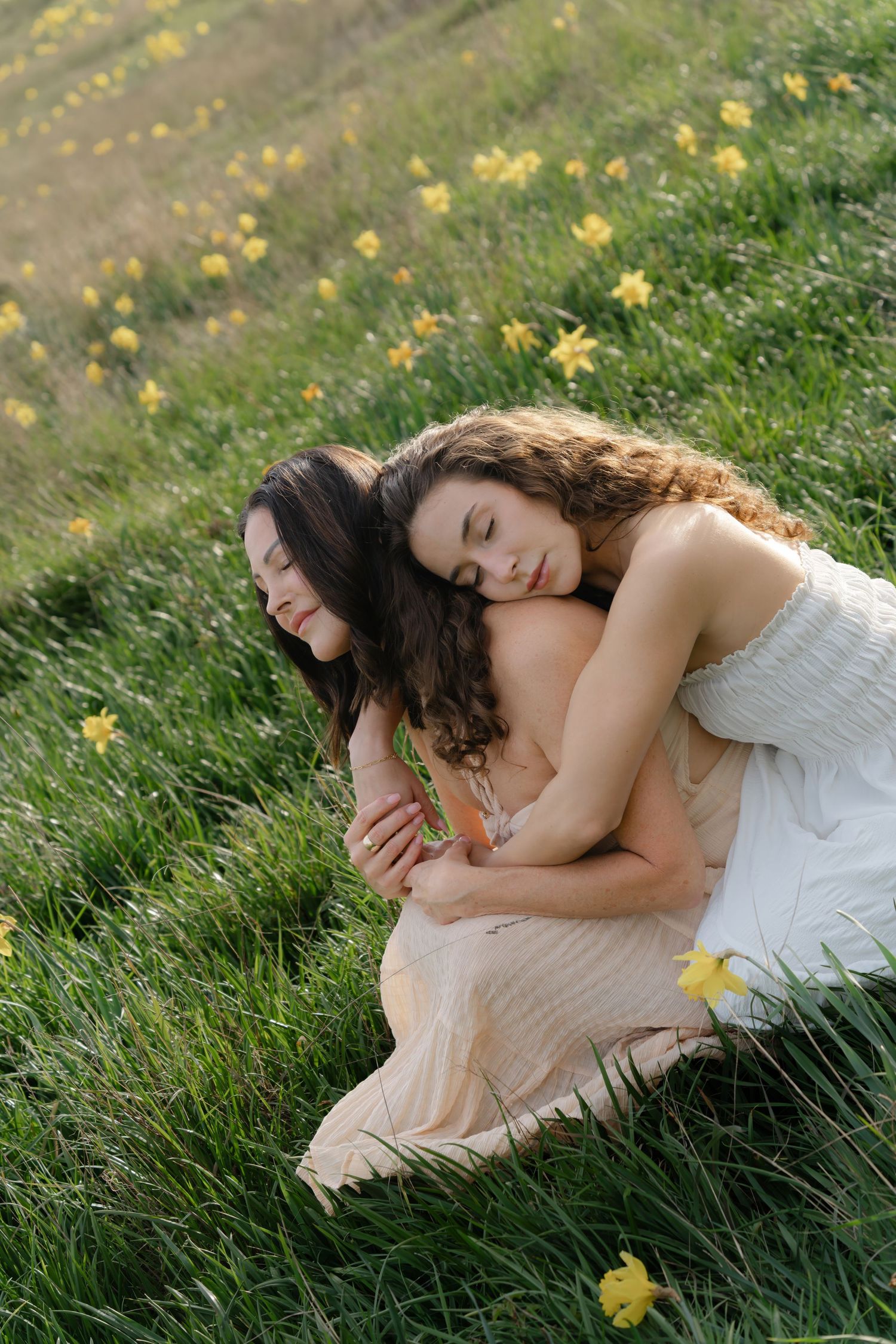 Two people lying in grass with yellow flowers on sunny day.