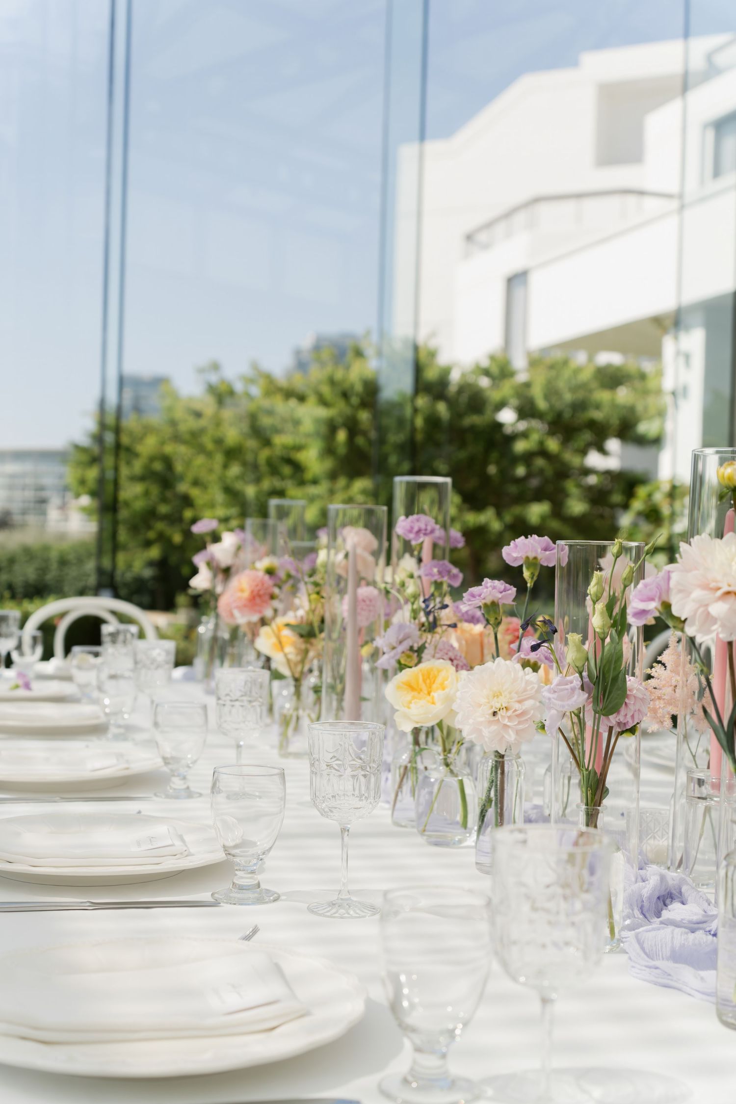Elegant table setting with delicate pink and purple flowers in crystal vases.