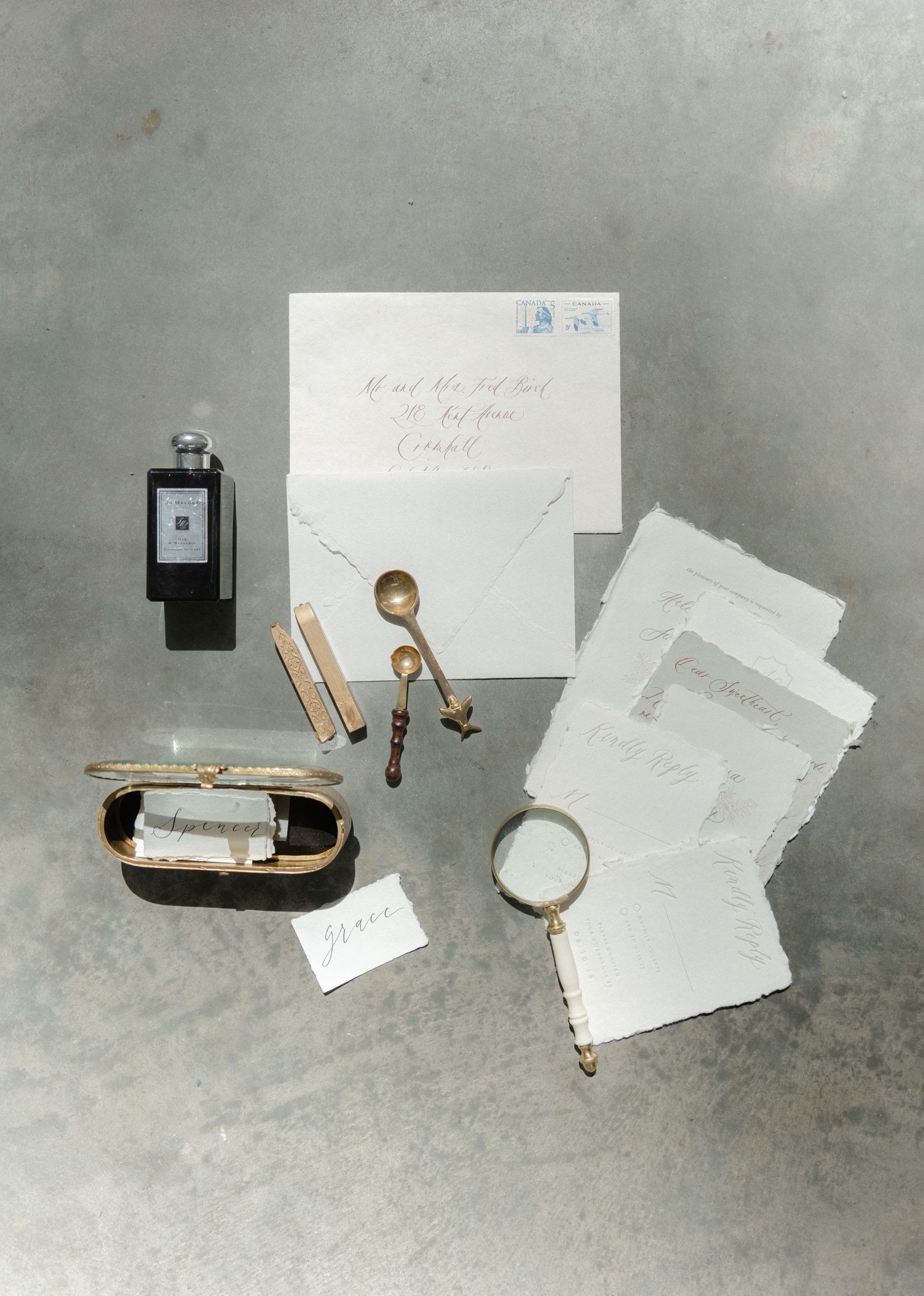 Minimalist flat lay of wedding stationery and accessories on concrete background.
