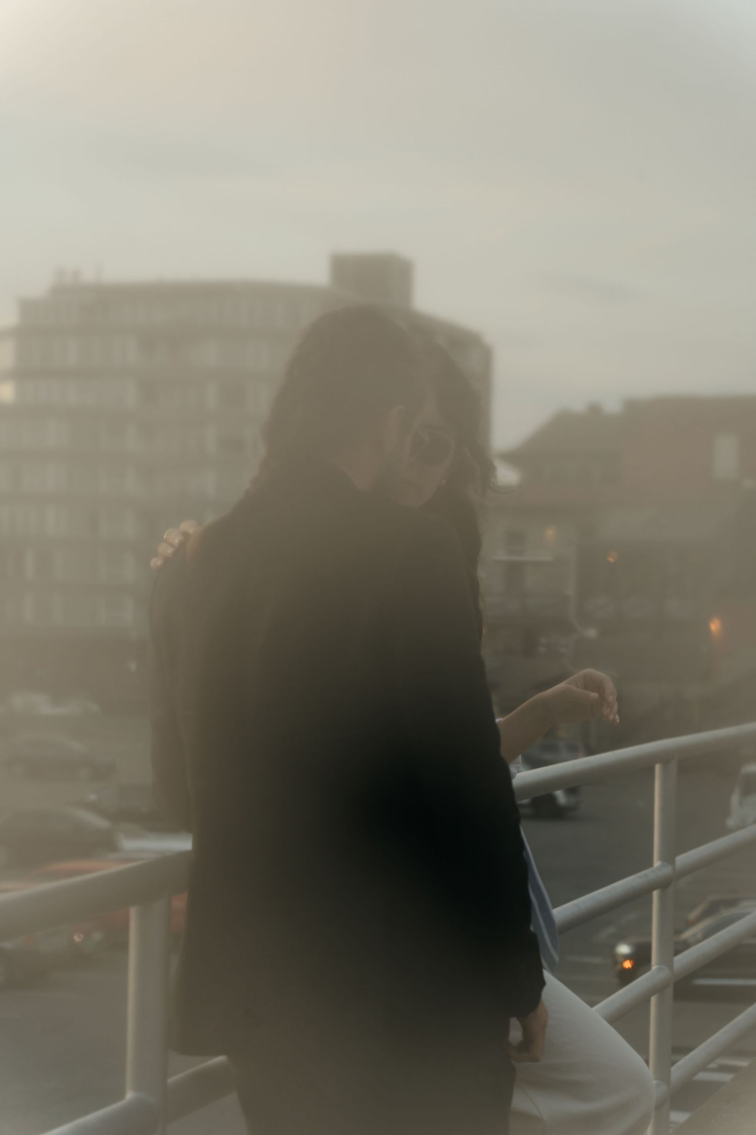 Moody silhouettes against city buildings at sunset on a balcony at Wharf street.