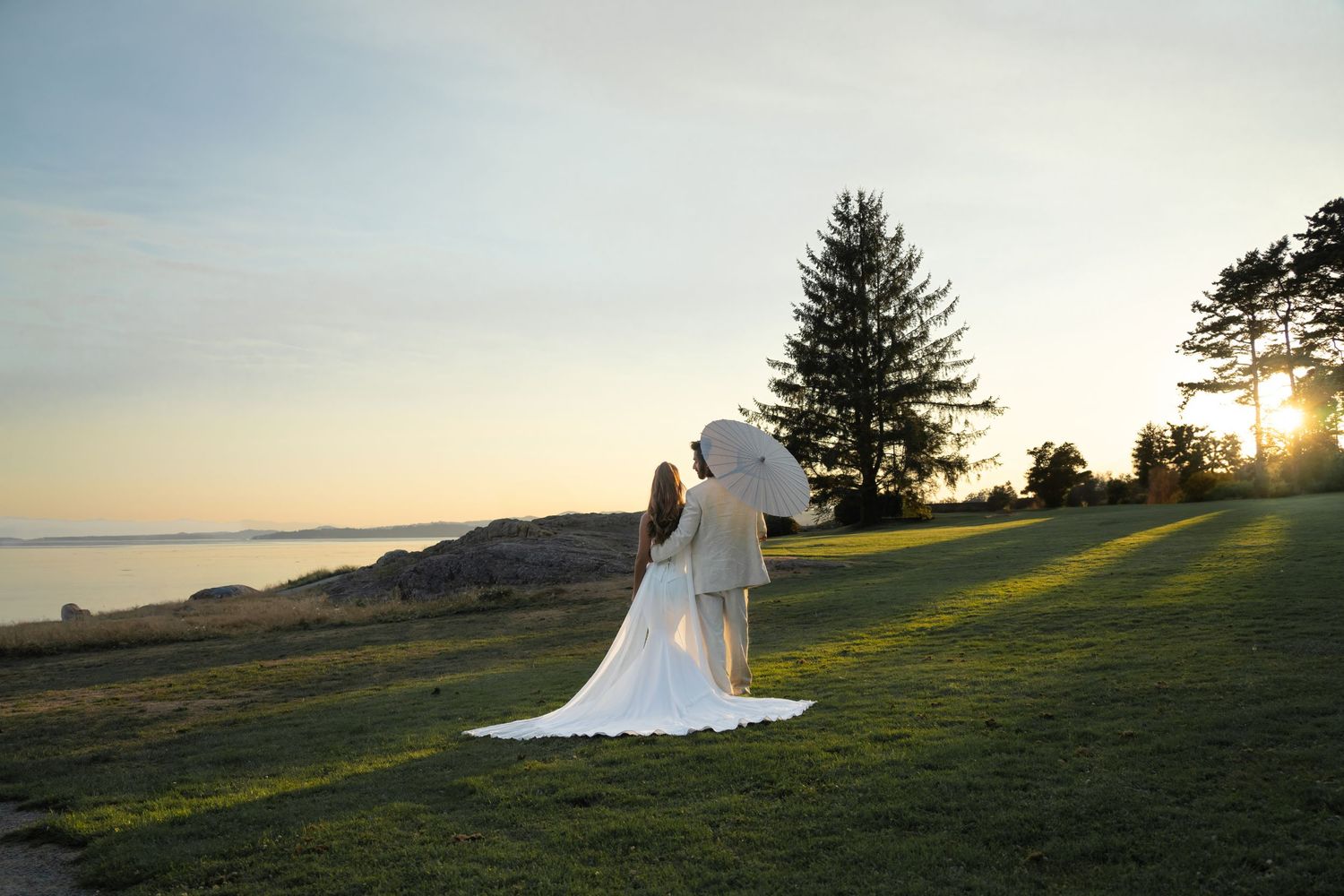 A flowing white wedding dress catches golden sunlight on a hilltop overlooking a misty valley at sunset. wedding photography Victoria