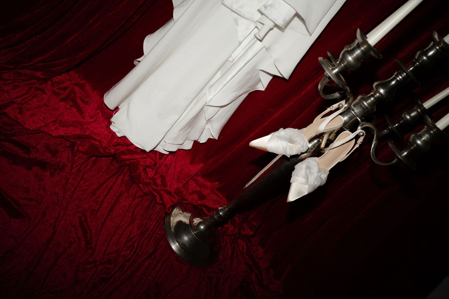 A row of white feathers arranged against a deep red velvet background with black objects creating dramatic contrast.