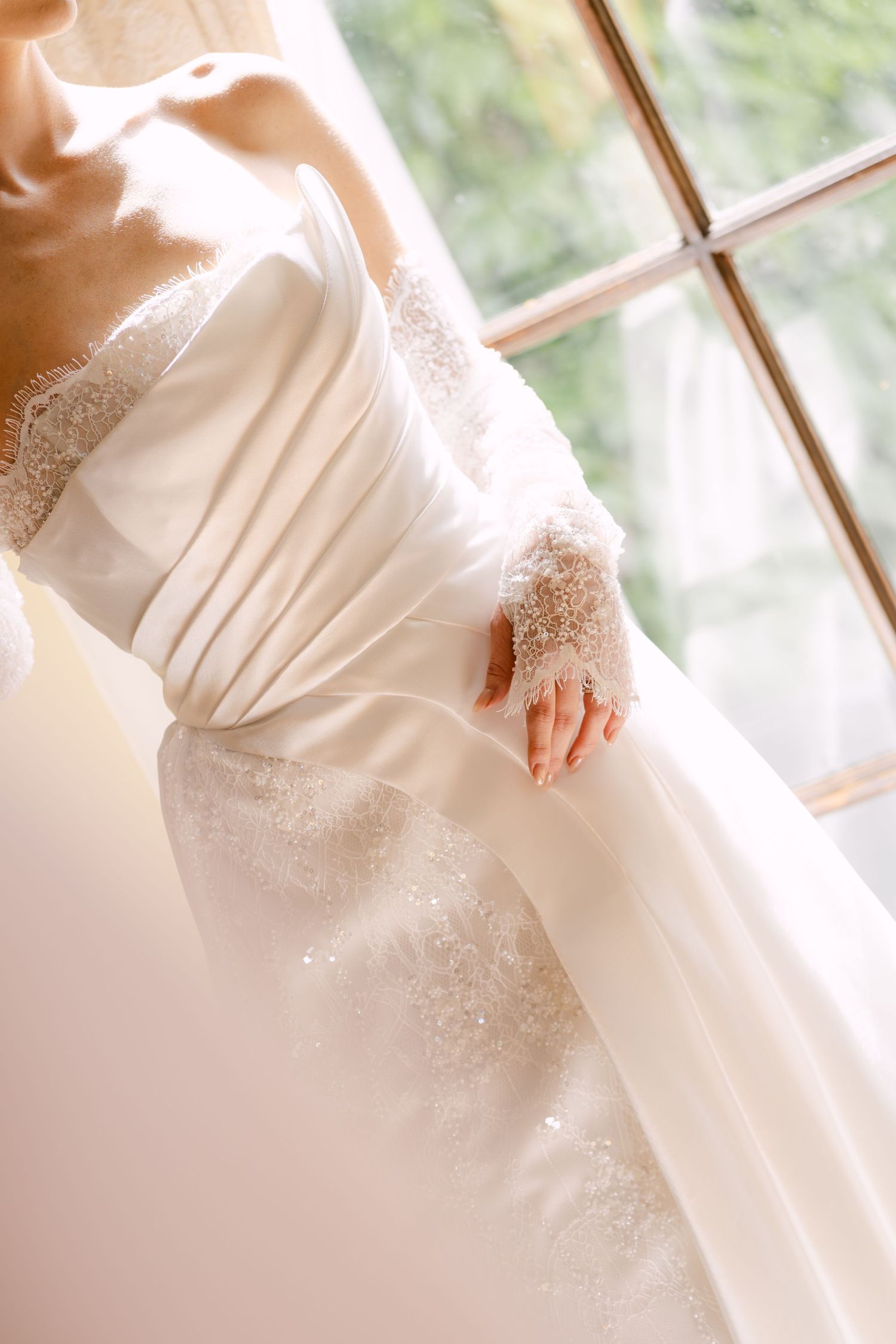 Close-up detail of elegant white lace long-sleeve wedding gown with intricate beaded embroidery.