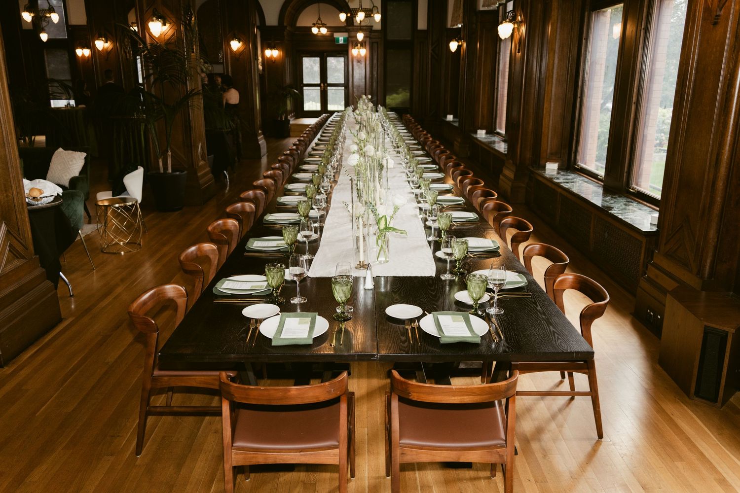 Long banquet hall with wooden chairs and dramatic lighting for wedding reception.