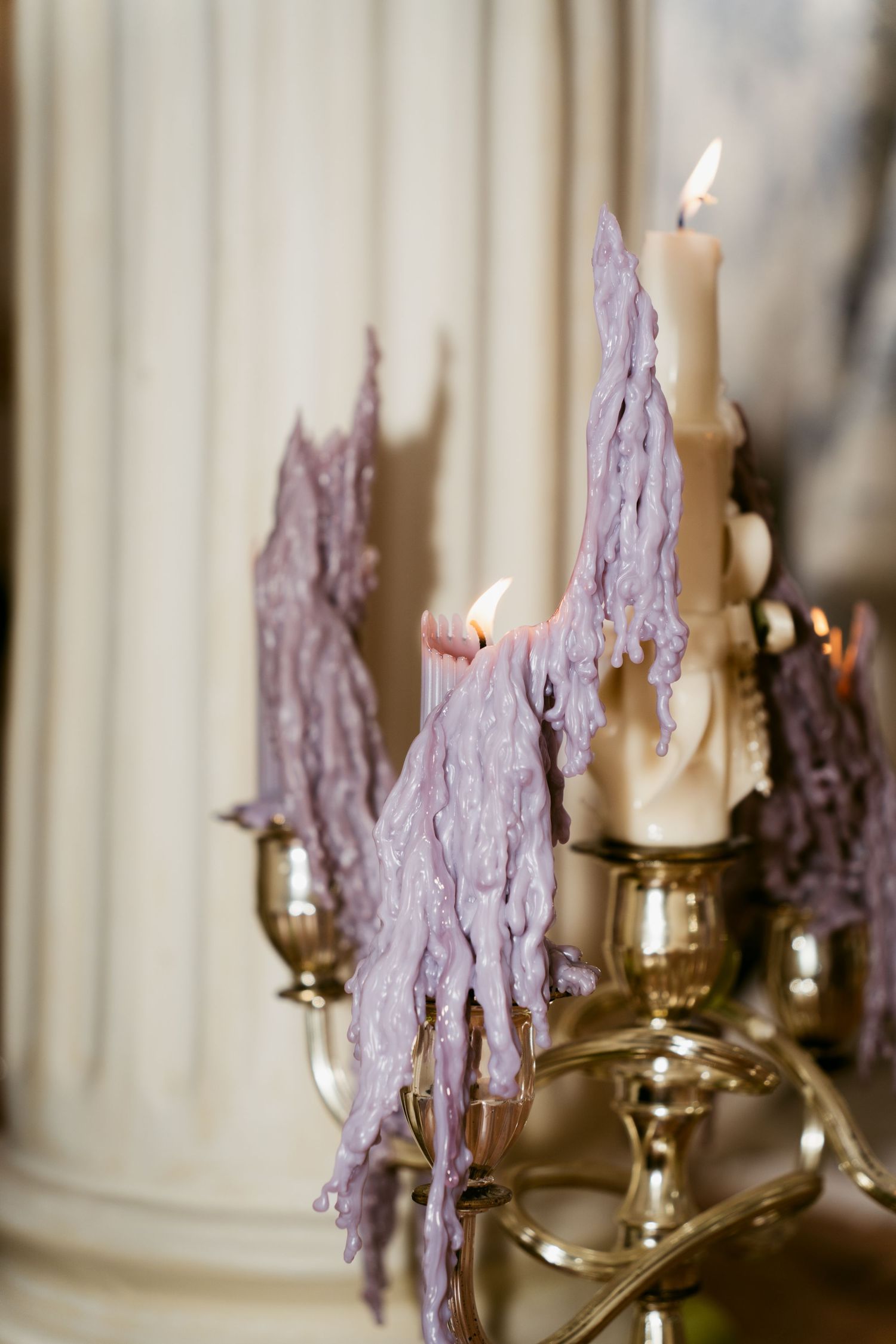 Lit candles in brass holders with delicate purple lace accents create an ethereal ambiance.