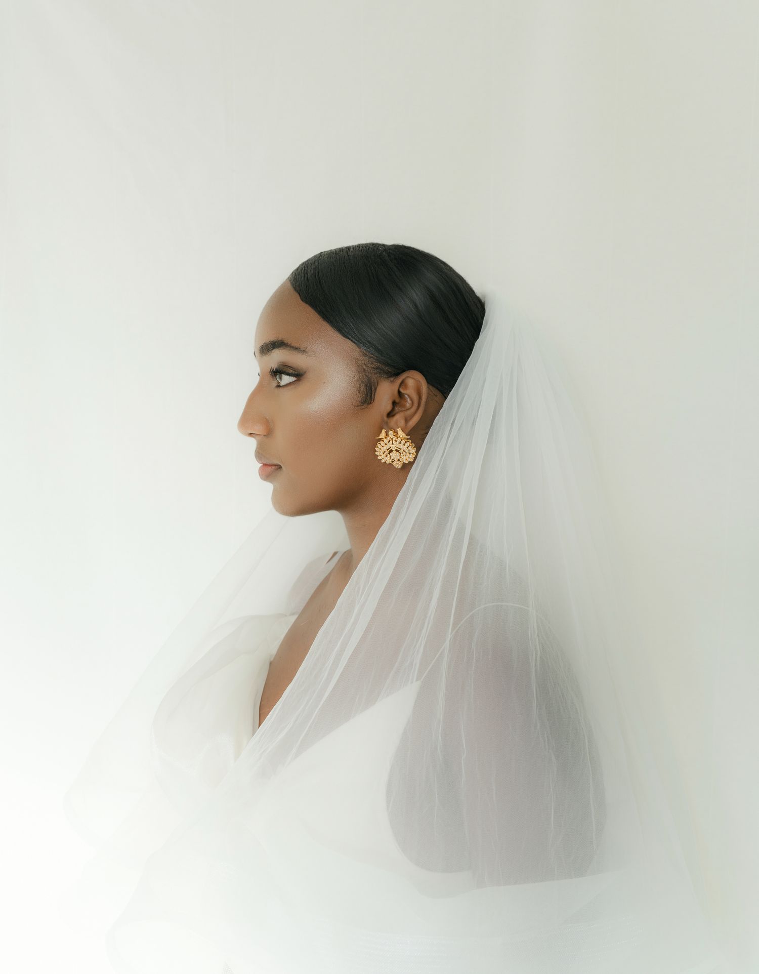 A minimalist portrait series showing three side profile views of a bride wearing an elegant veil against a white background.