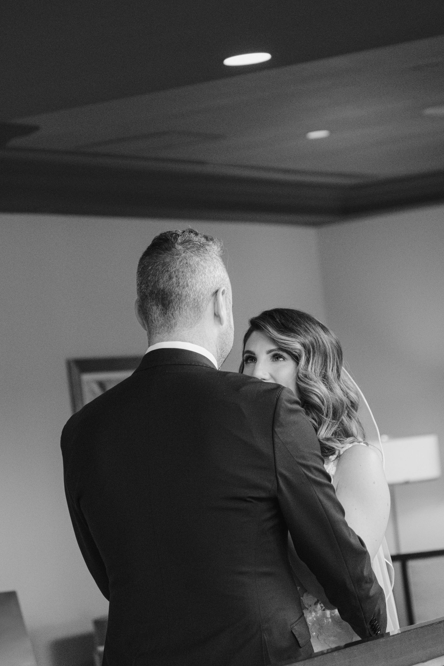 Black and white photo of a bride and groom embracing tenderly during their wedding day indoors at Fairmont Empress Hotel Victoria BC