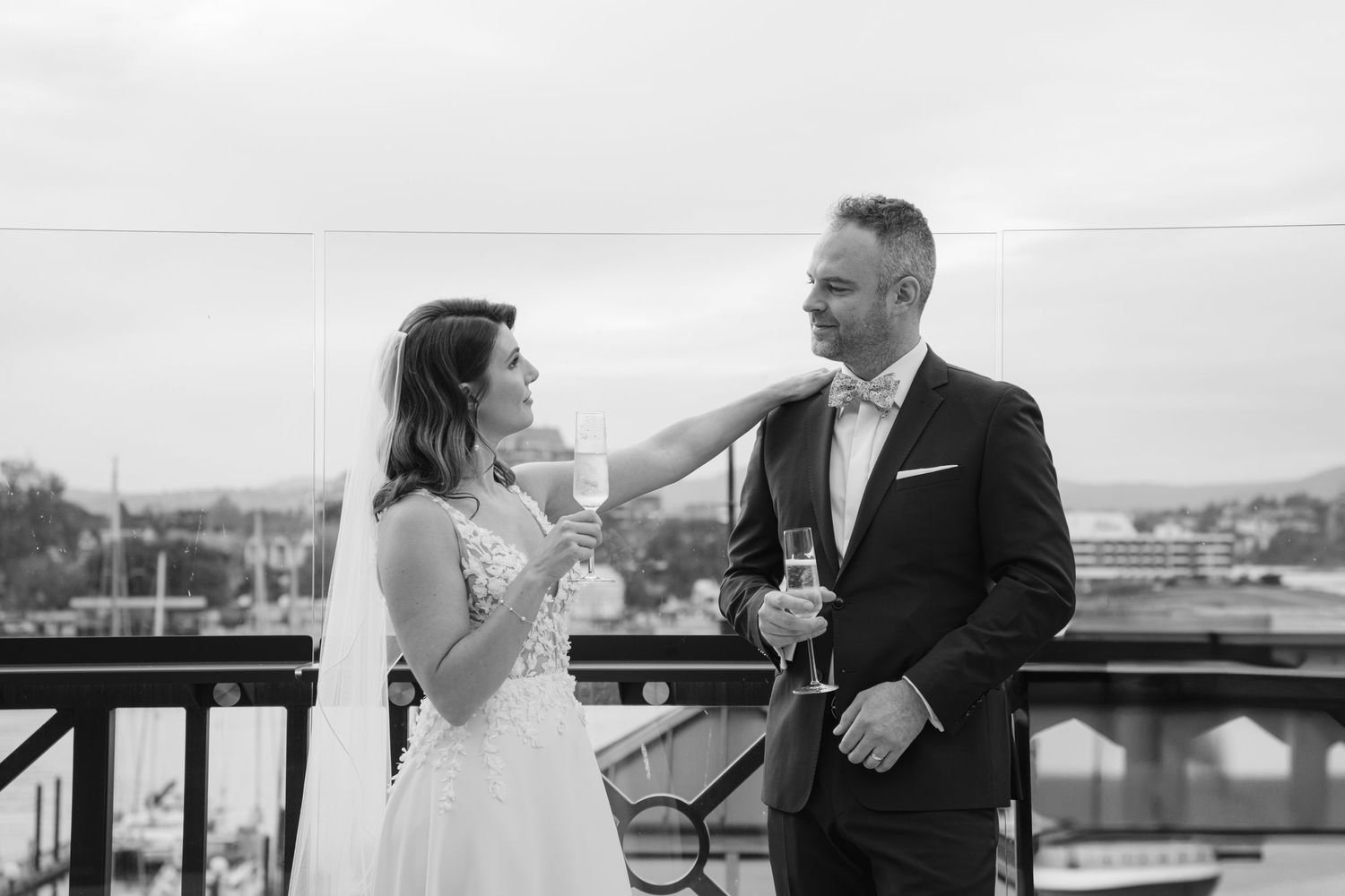Black and white photo of newlyweds sharing drinks on an outdoor balcony at Fairmont Hotel Victoria BC