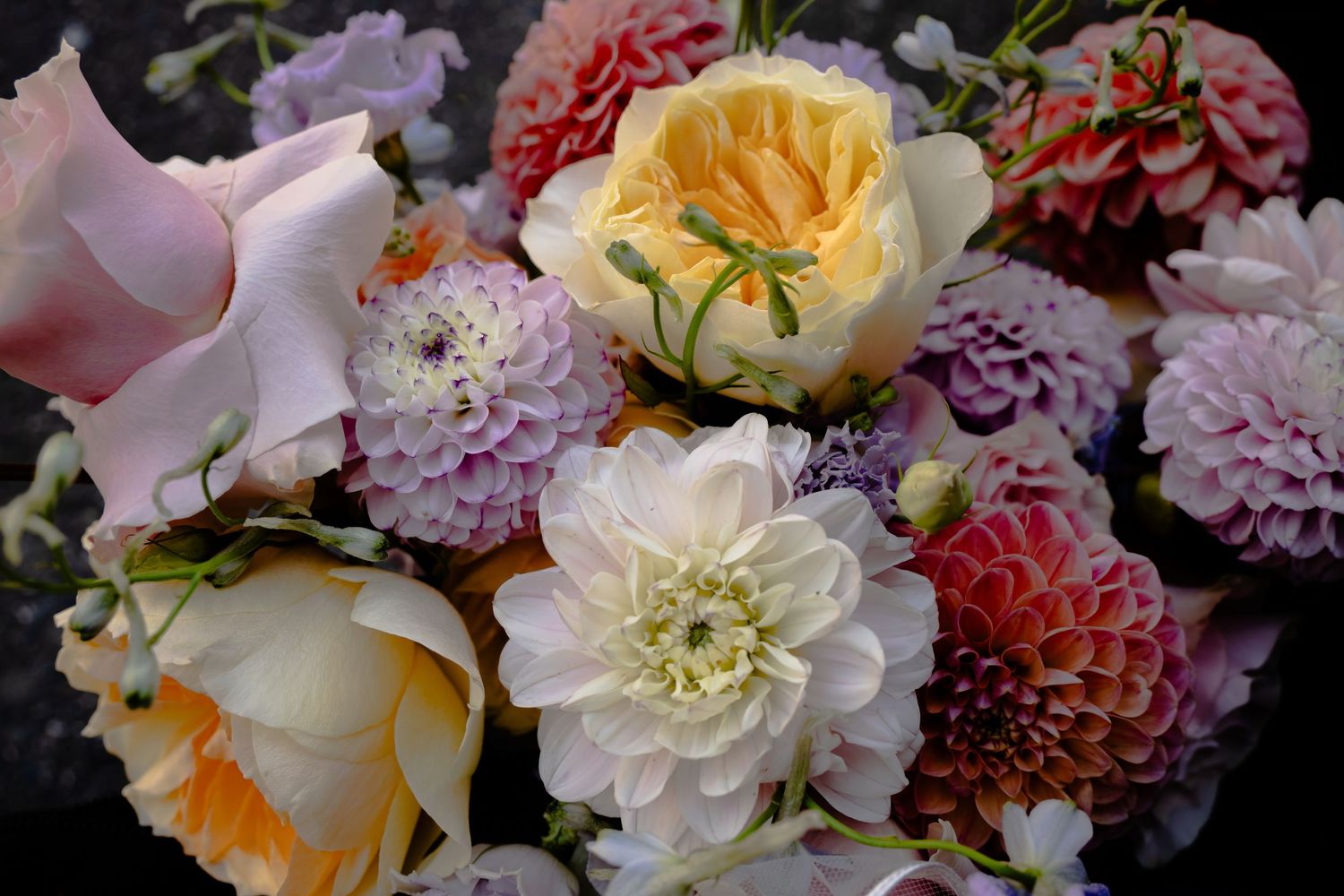 Beautiful floral arrangement featuring pink, yellow and white garden roses and dahlias.