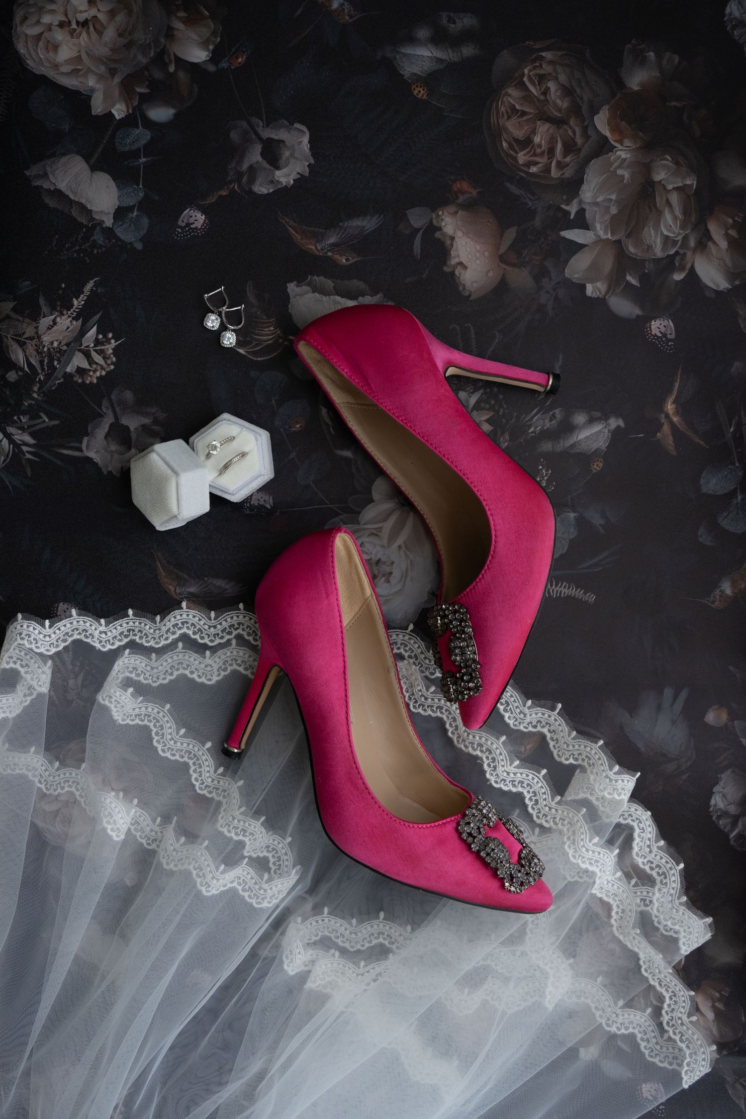 Hot pink bridal heels with crystal embellishments photographed against white lace fabric.