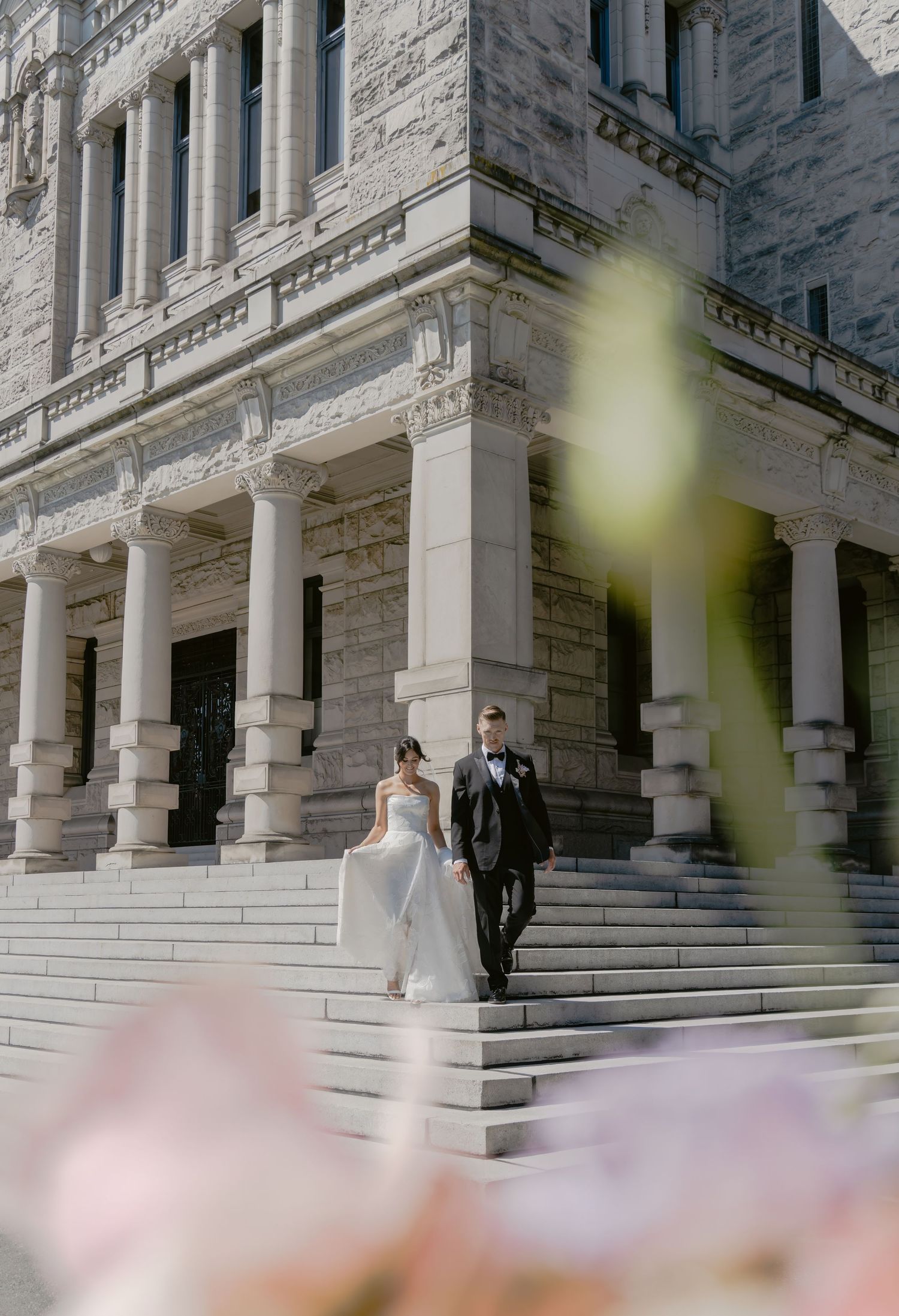A grand stone building with white columns serves as an elegant wedding venue backdrop at British Columbia Parliment Building