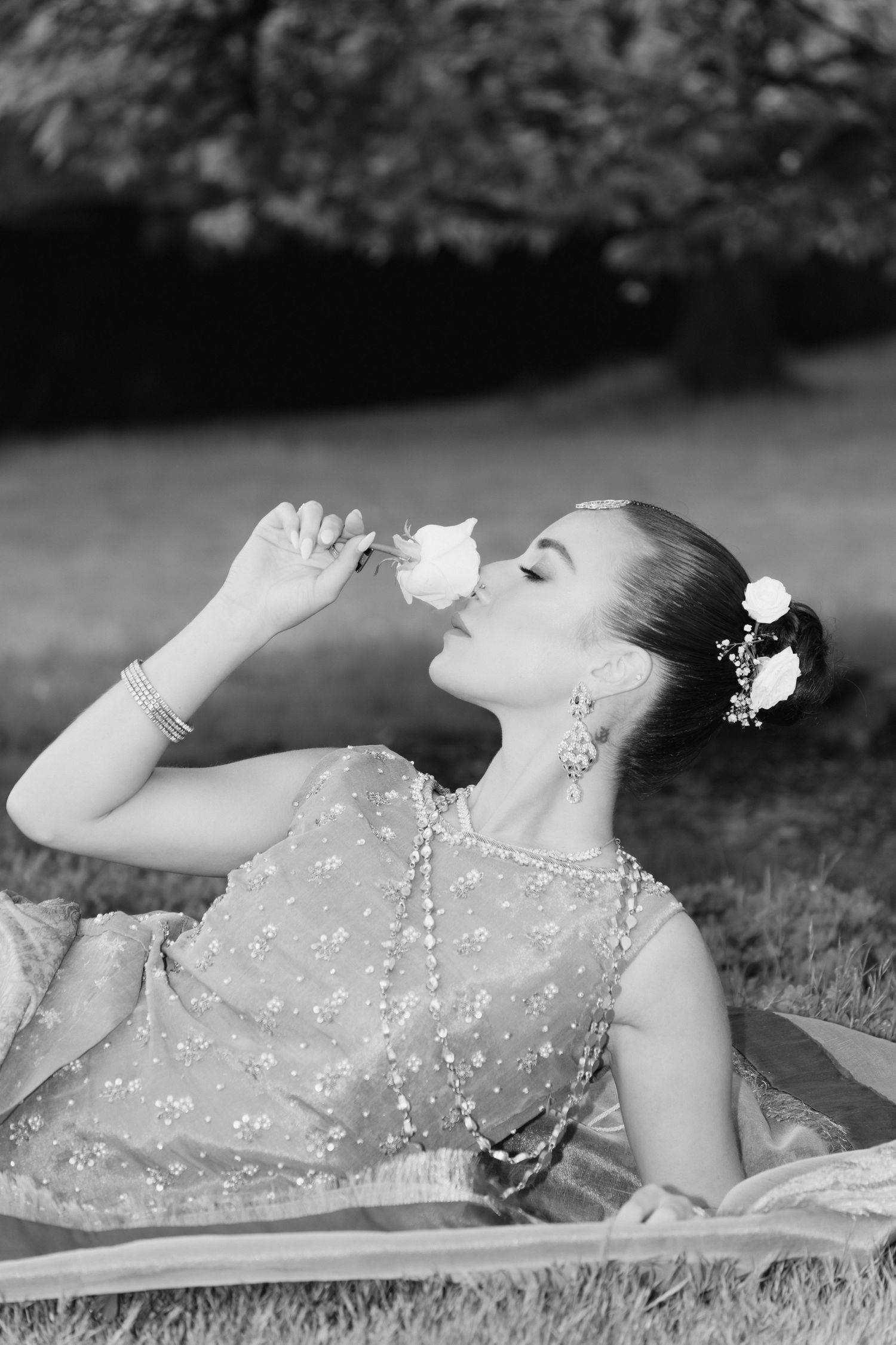 Black and white art photos of person in embellished dress lying on grass.