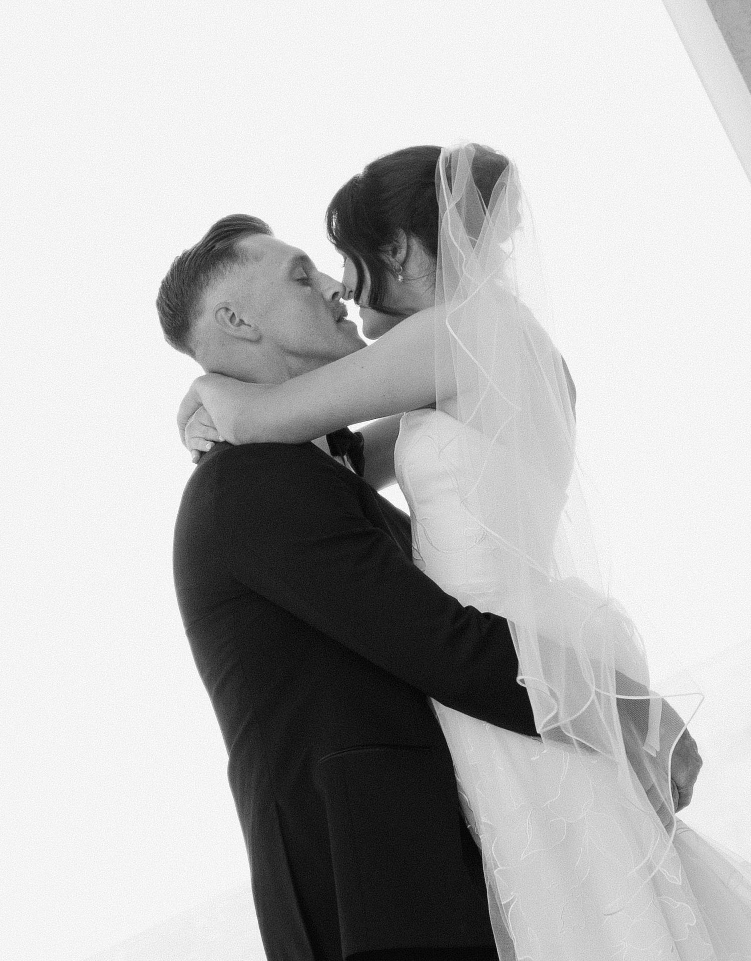 A romantic black and white silhouette of newlyweds sharing a kiss.