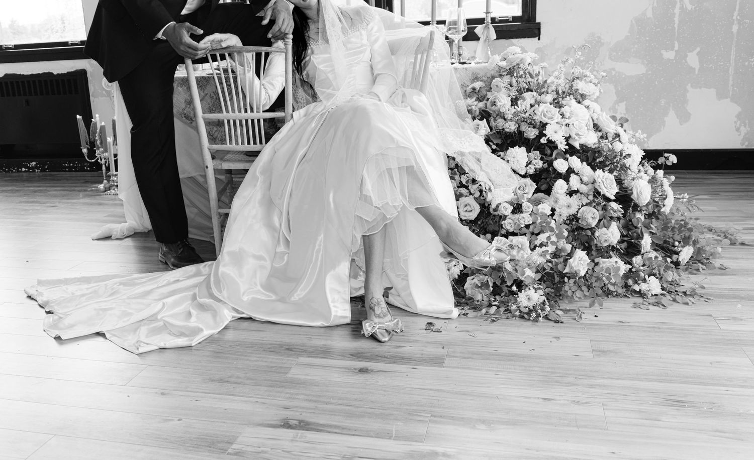 Black and white wedding photography scene with dramatic lighting and floral decor.