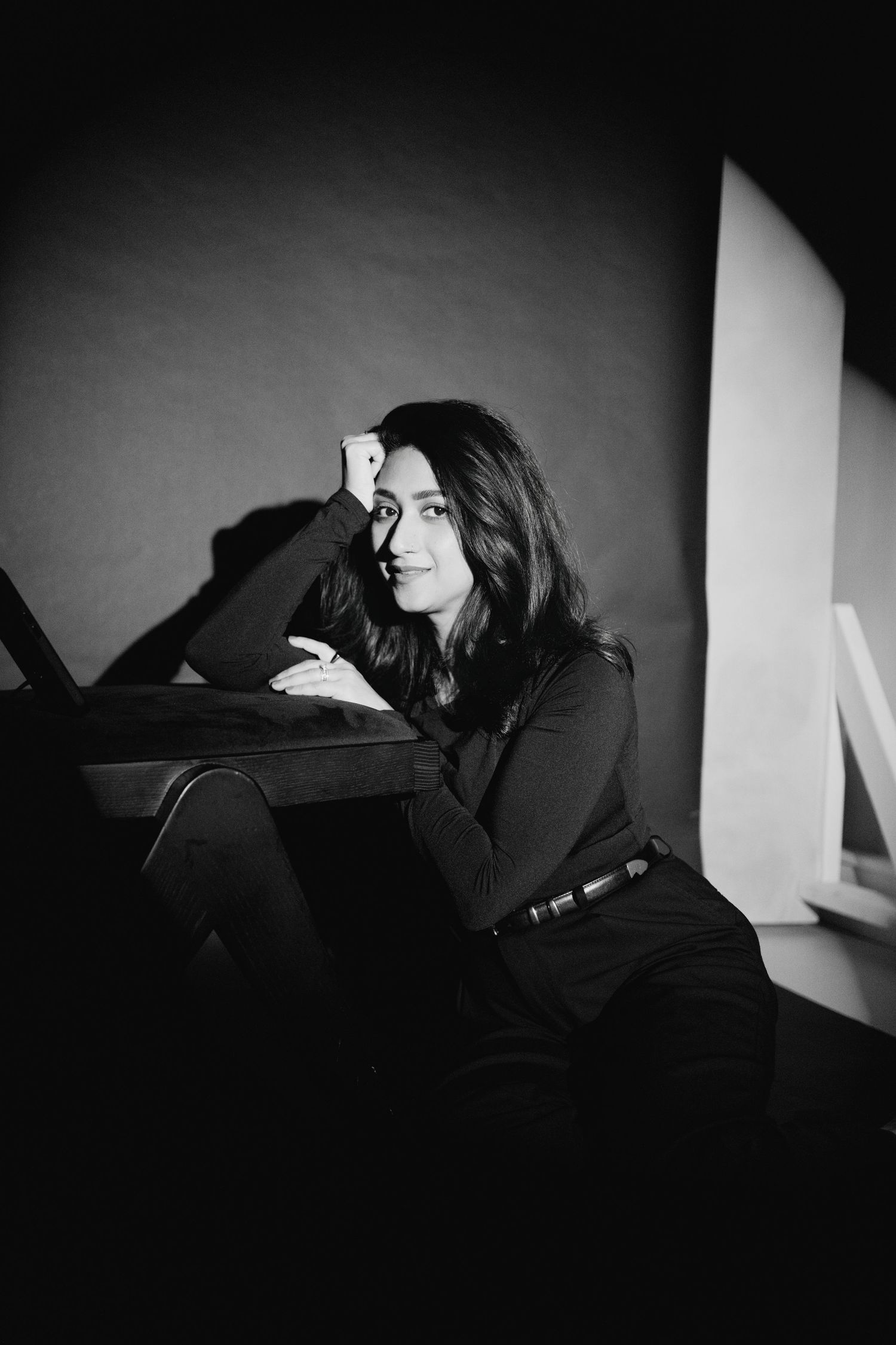 A series of black and white photos showing a person reclining in darkness with dramatic shadows and contrast.