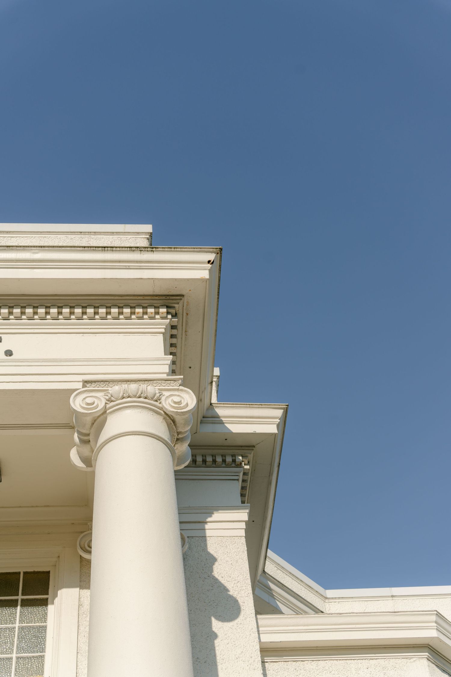 Classical white building facade with ornate columns against blue sky.