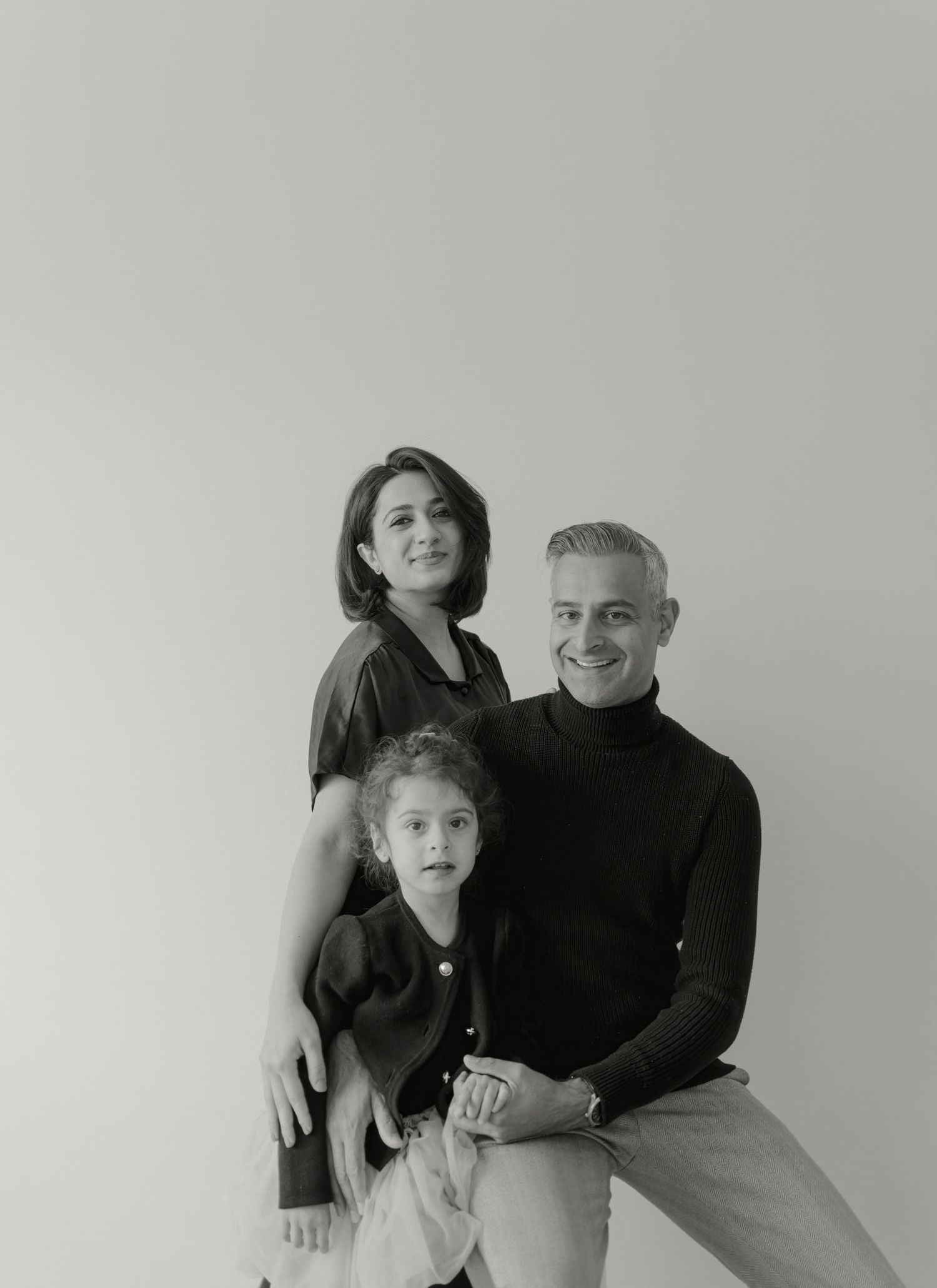 Family portrait in black and white against minimal background.