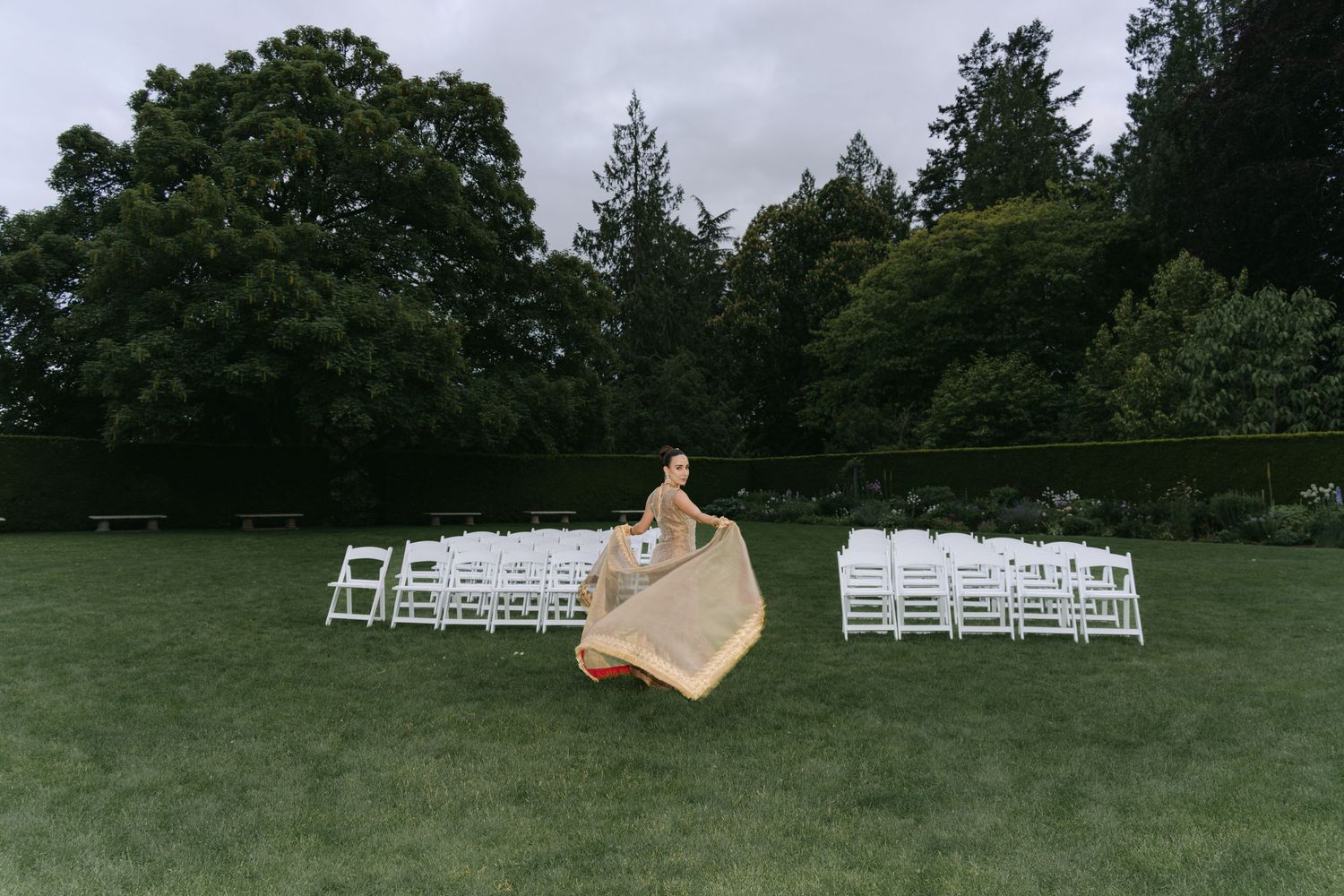 Outdoor wedding ceremony setup with white chairs arranged on green lawn.
