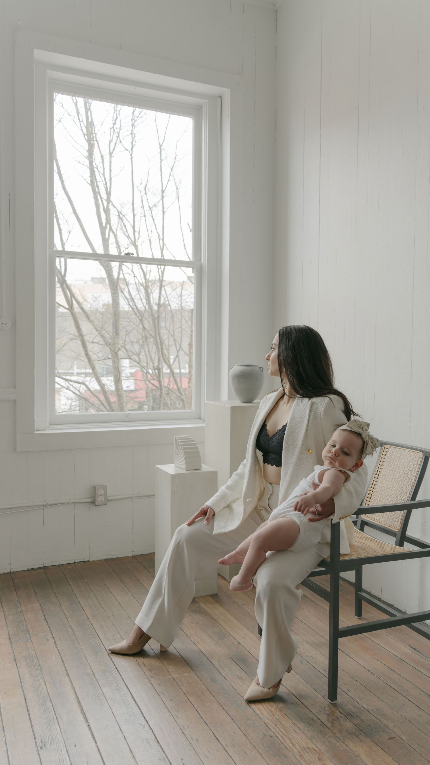Series of relaxed moments by large windows in a bright white room with wooden floors.
